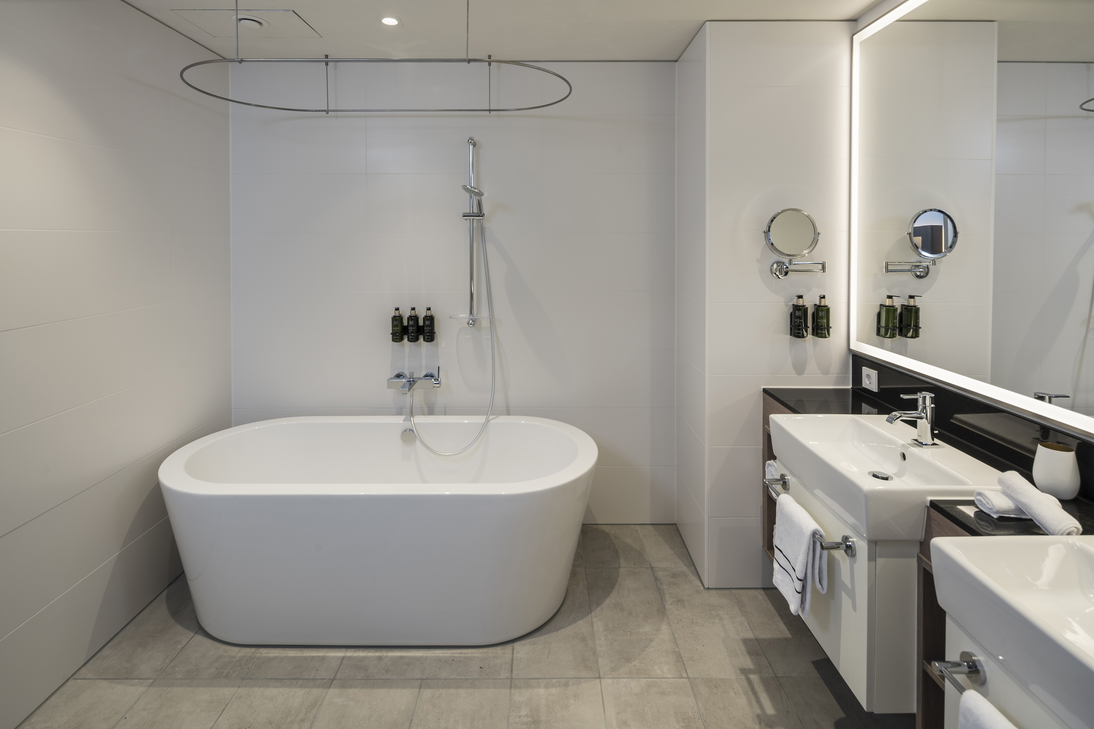 Modern hotel bathroom with freestanding tub, shower, and double vanity.