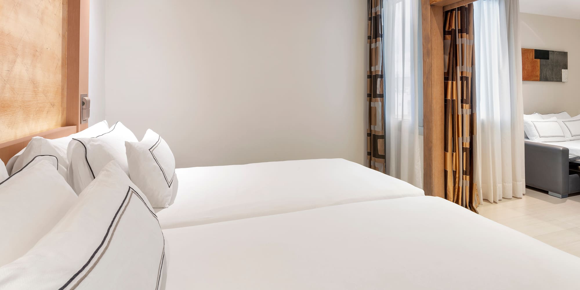 a room with white bedding and curtains