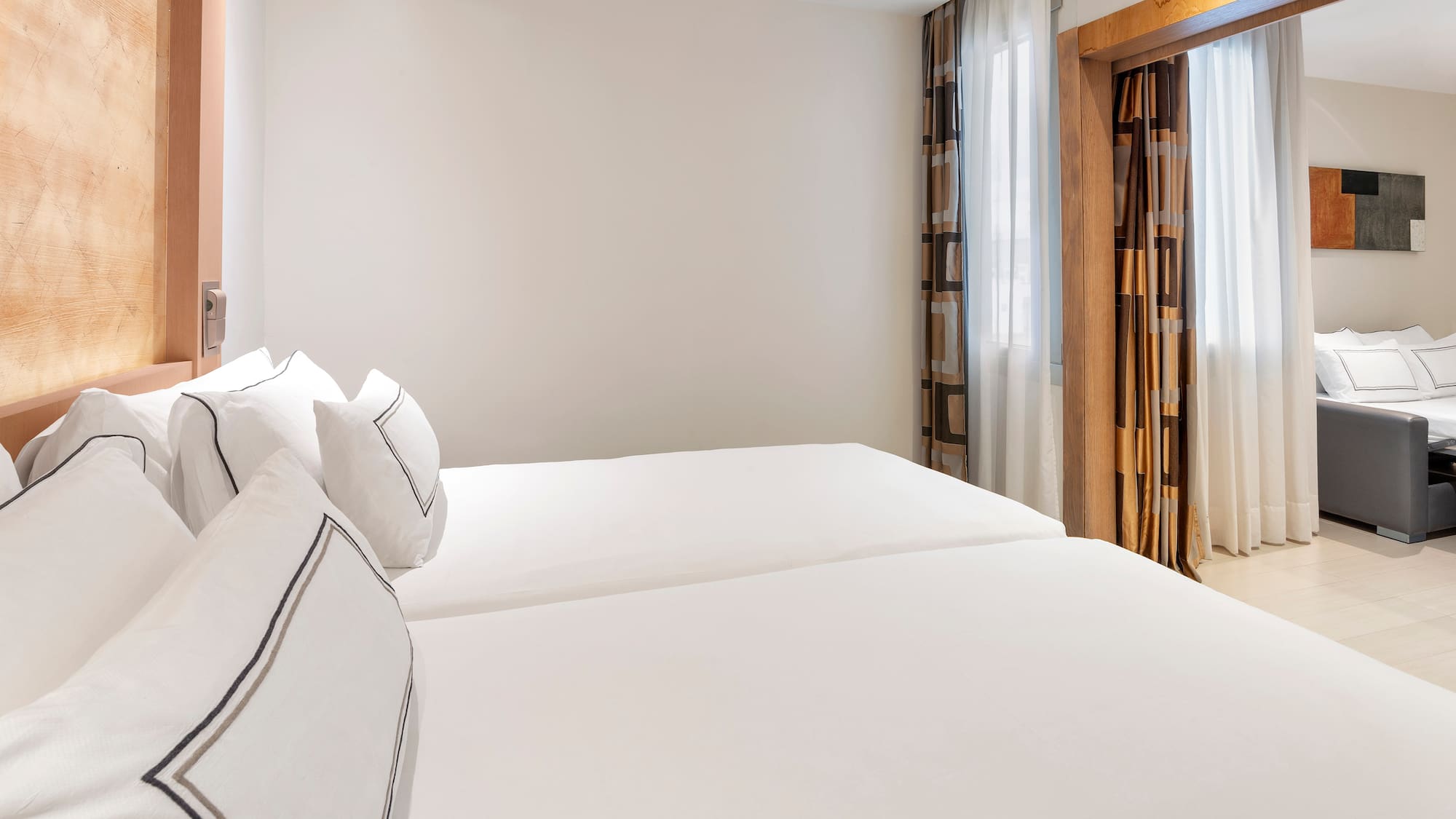 a room with white bedding and curtains