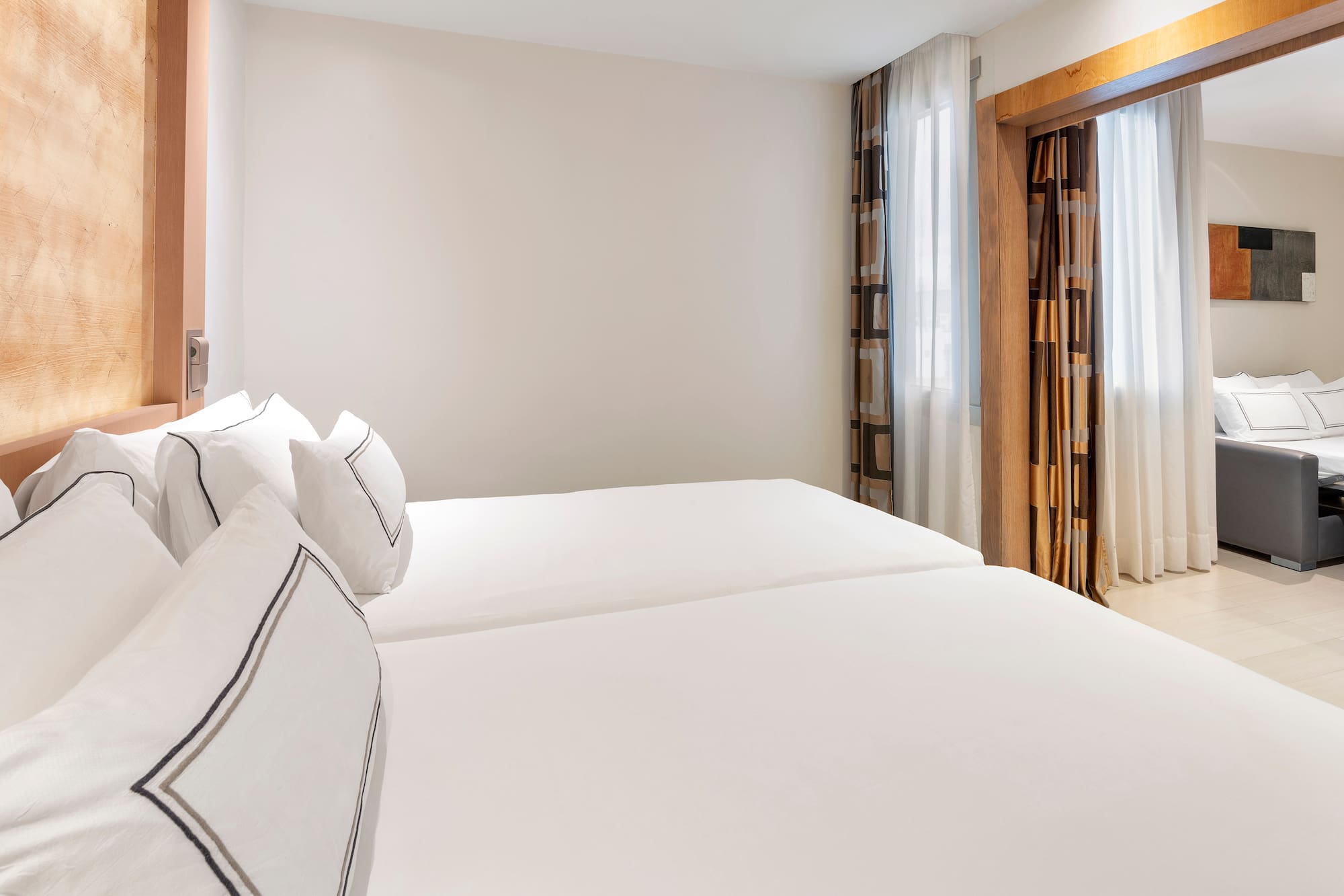 a room with white bedding and curtains