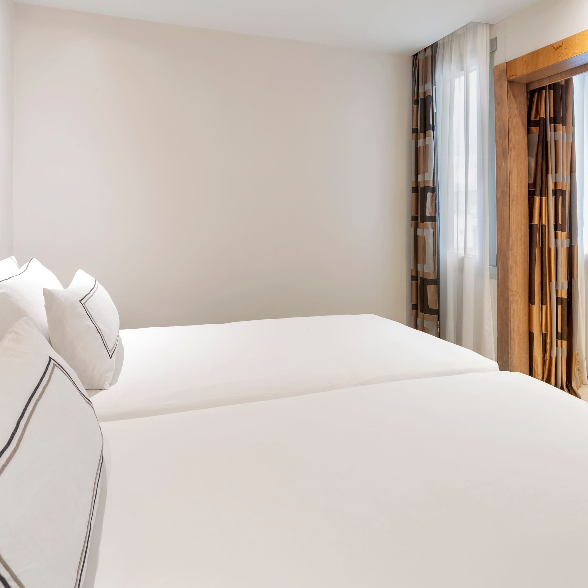 a room with white bedding and curtains