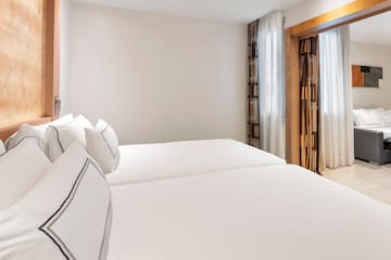 a room with white bedding and curtains