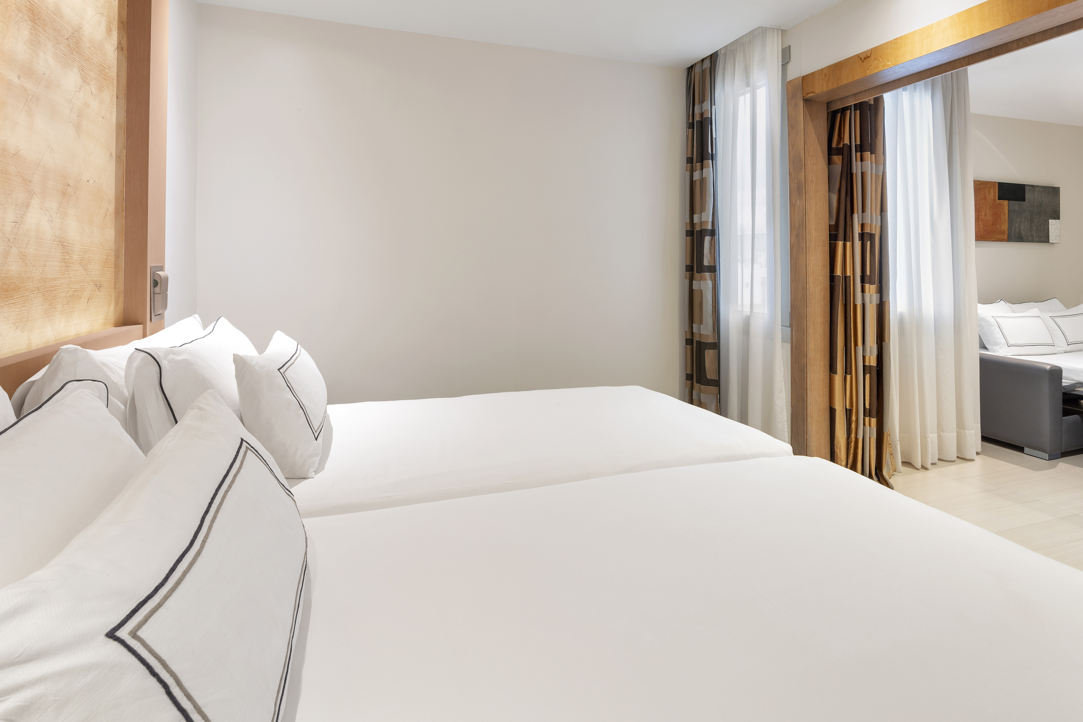 a room with white bedding and curtains