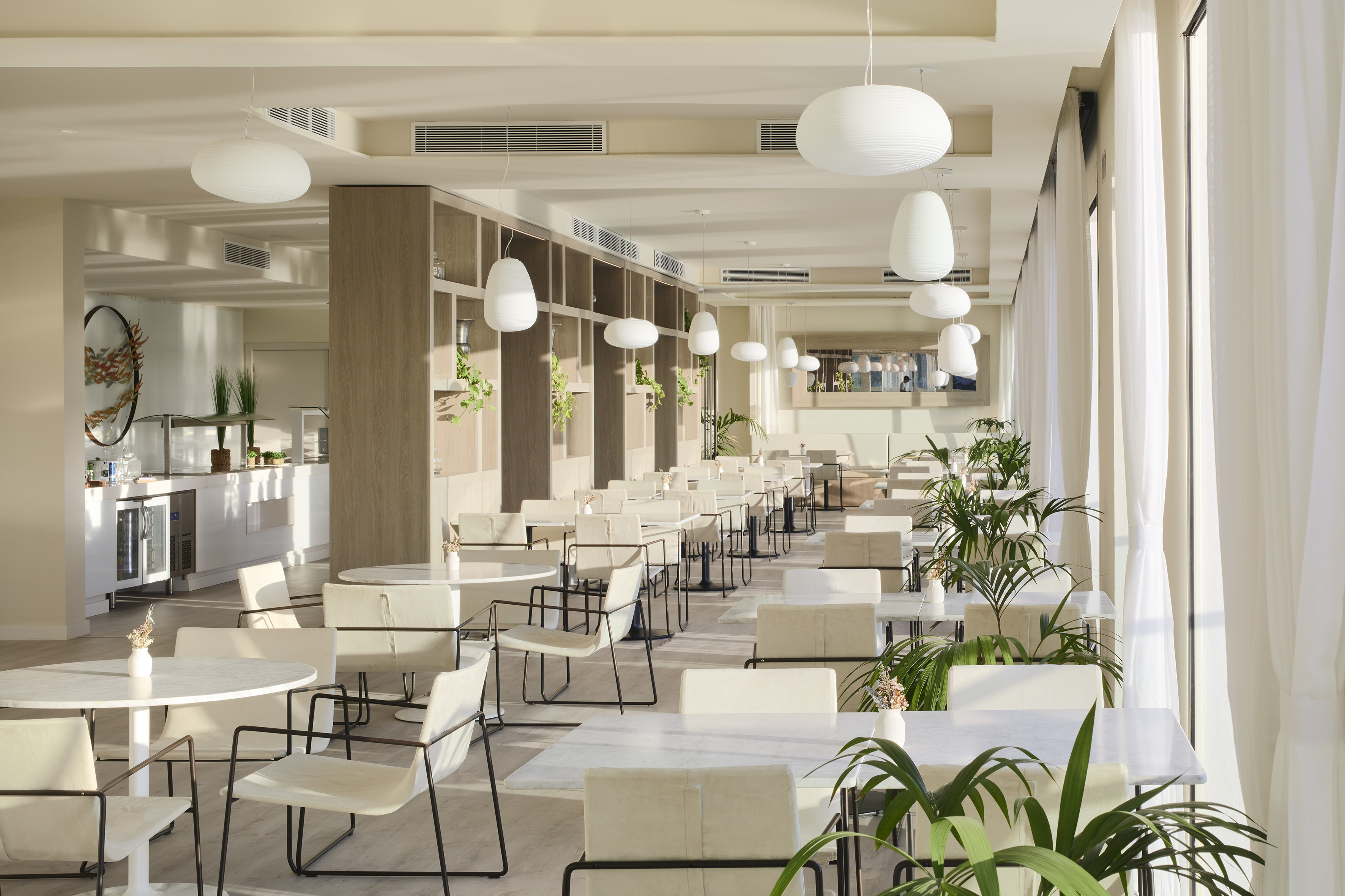 Bright modern restaurant dining area with white furniture and plants.