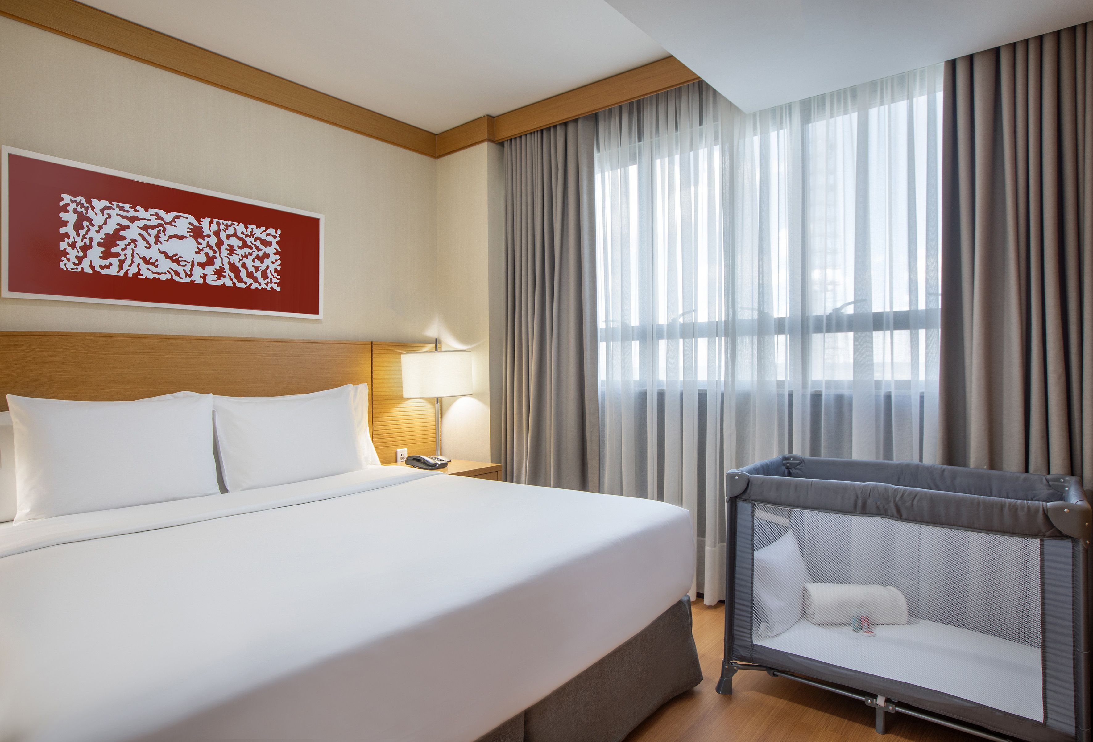 Family hotel room with king bed and baby crib.