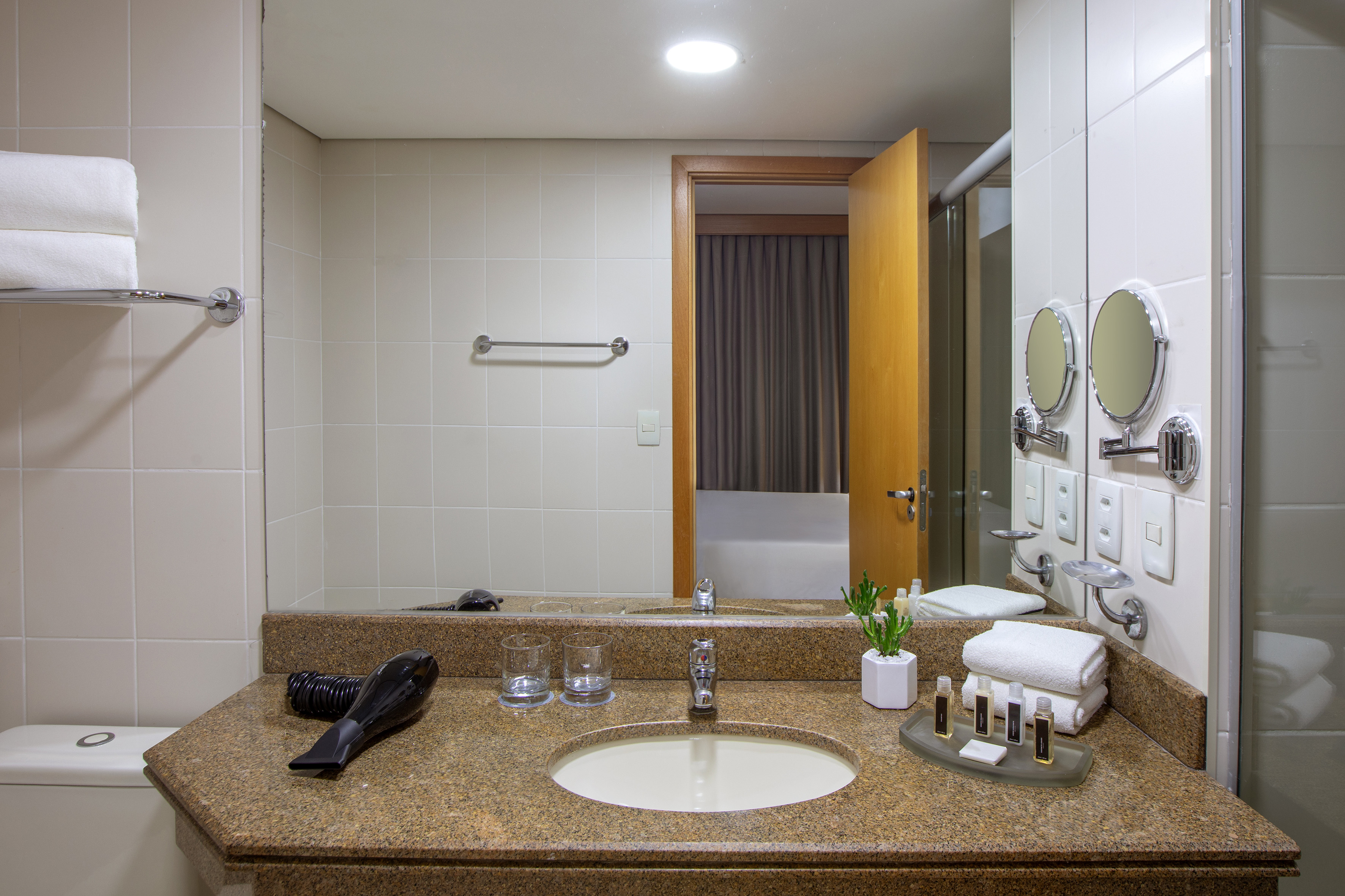 Hotel bathroom with granite vanity, sink, mirror, and modern amenities.