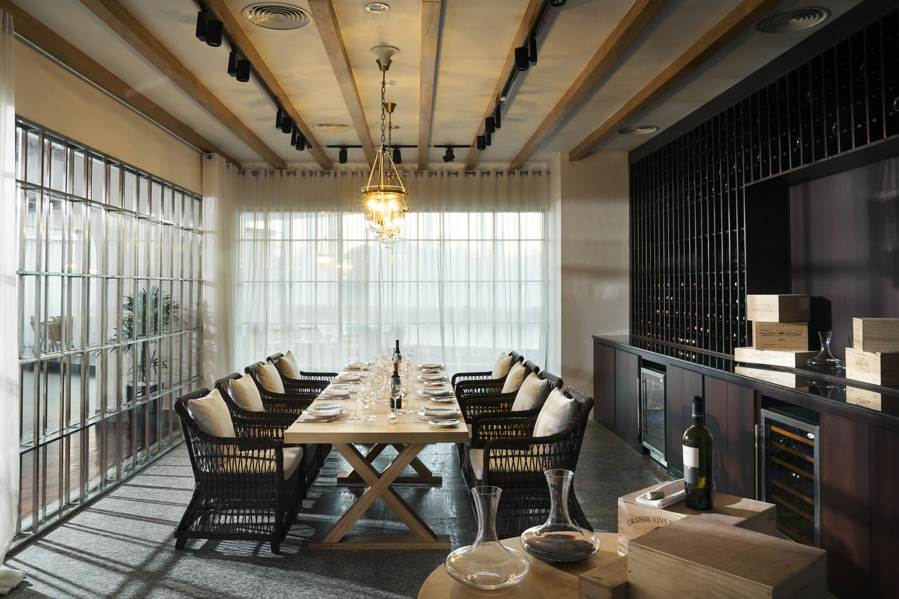 Elegant private dining room with long table, wicker chairs, and wine storage.
