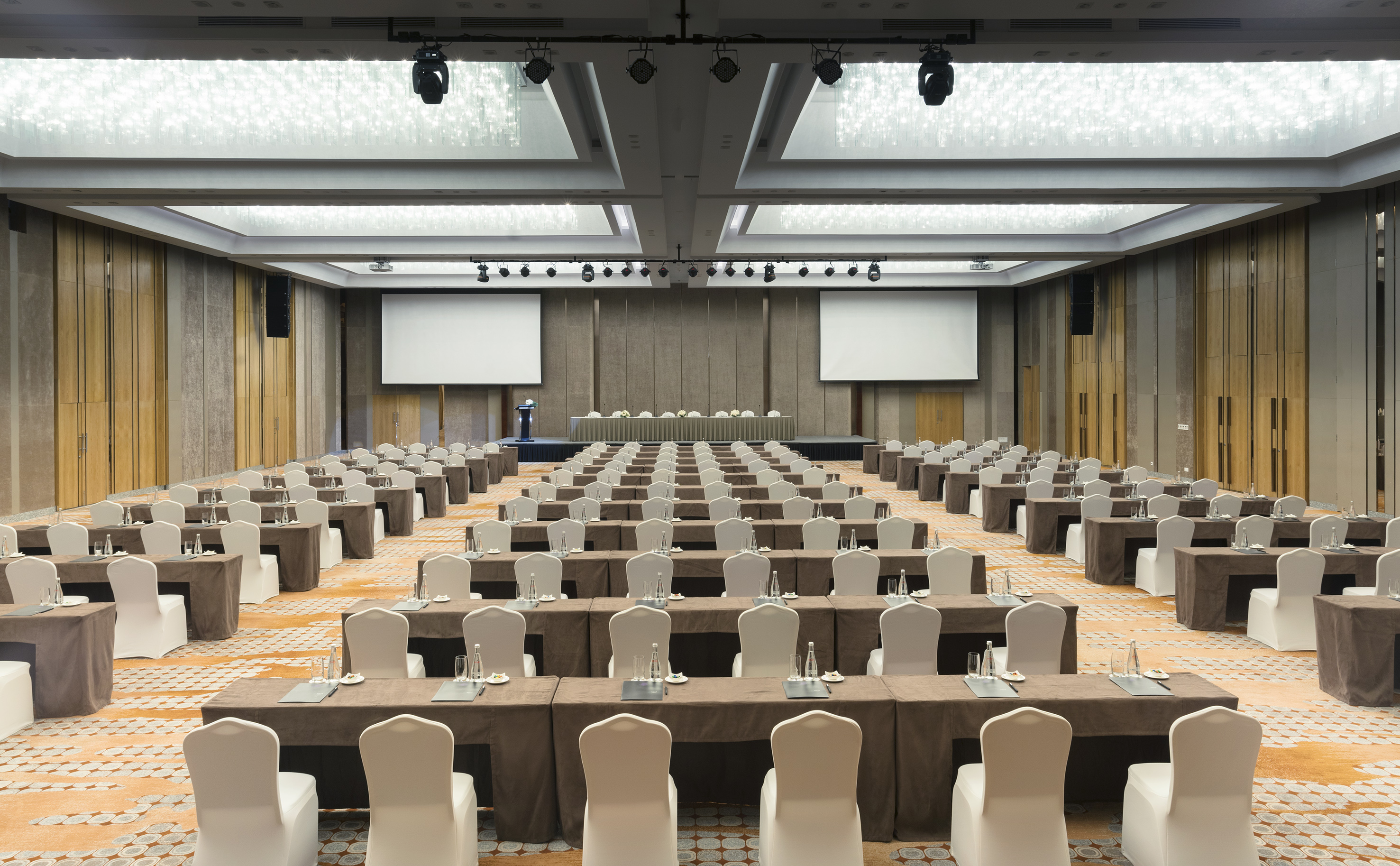 Empty large conference room with classroom style seating and two projector screens.