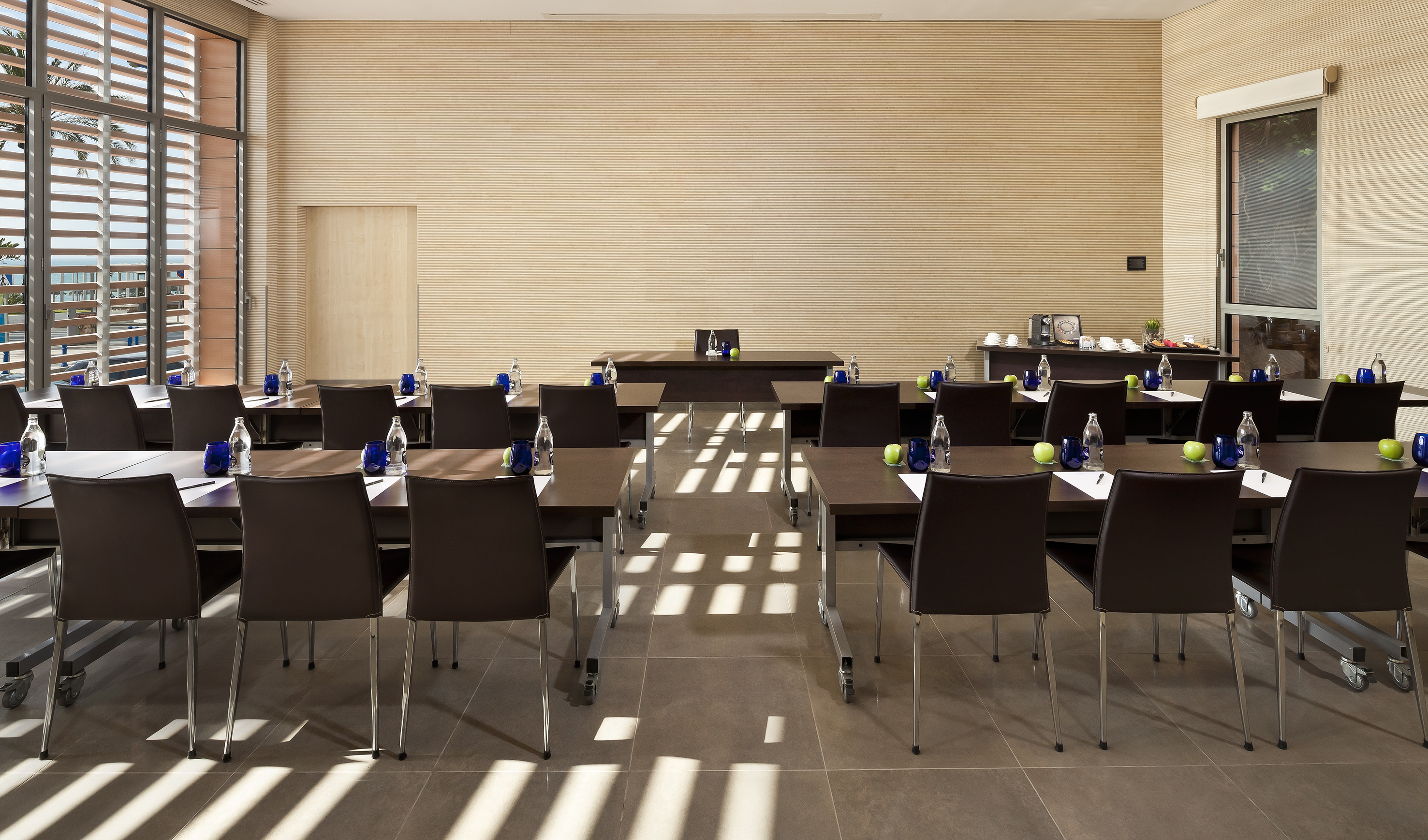 Modern conference room with individual tables, refreshments, and ocean view.