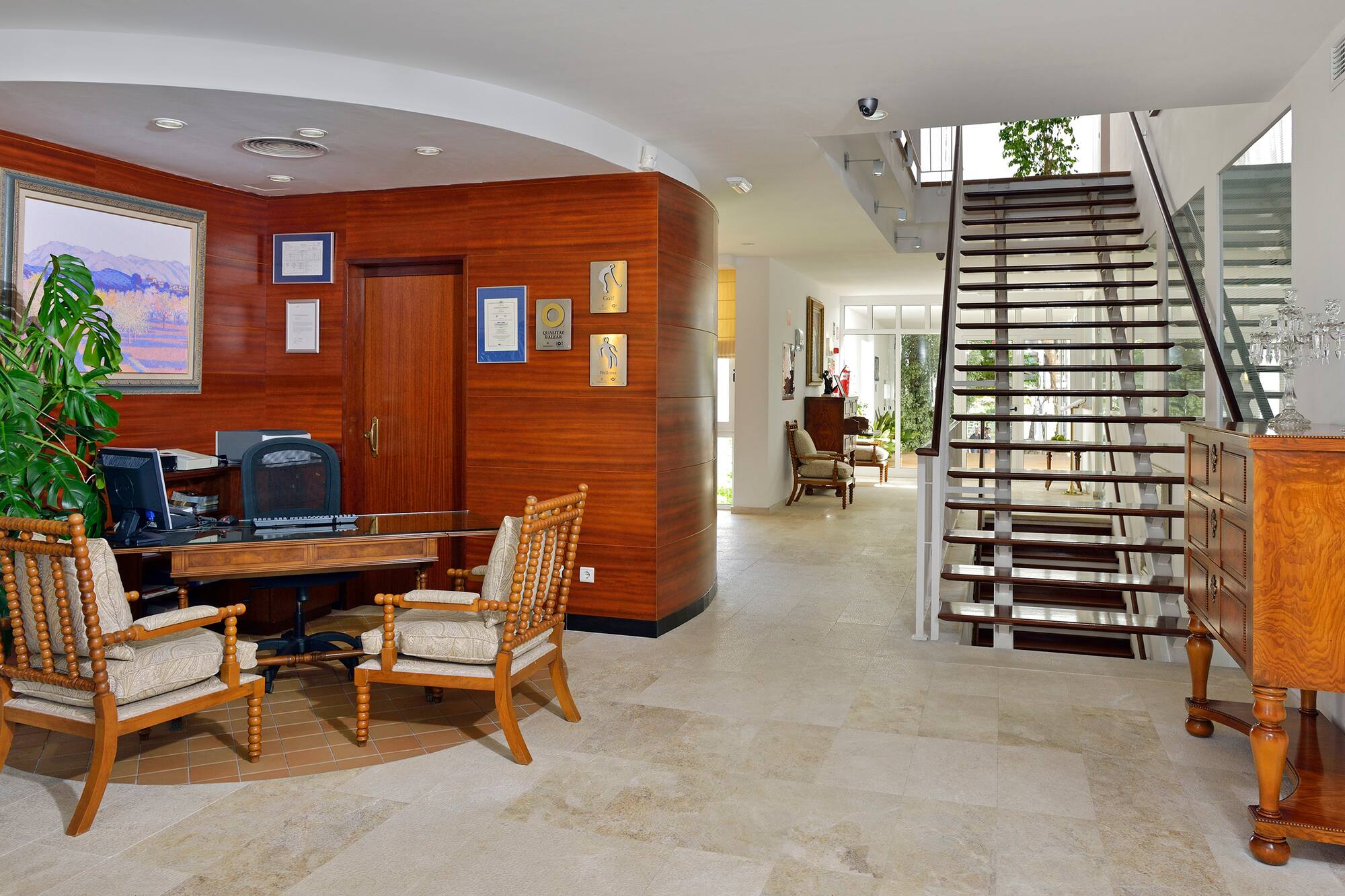 Spacious reception area with wooden desk, guest chairs, and modern staircase.