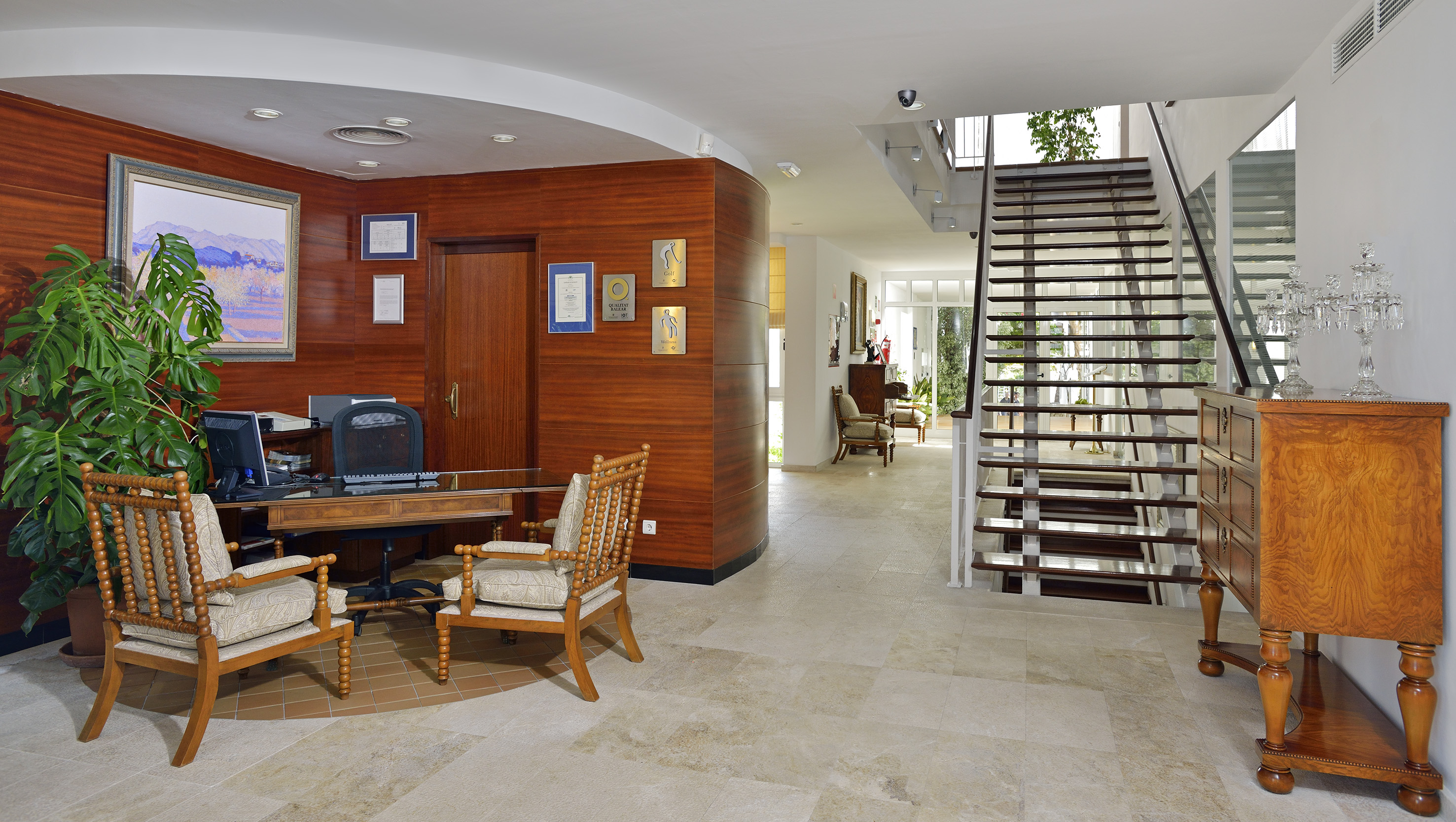 Spacious reception area with wooden desk, guest chairs, and modern staircase.