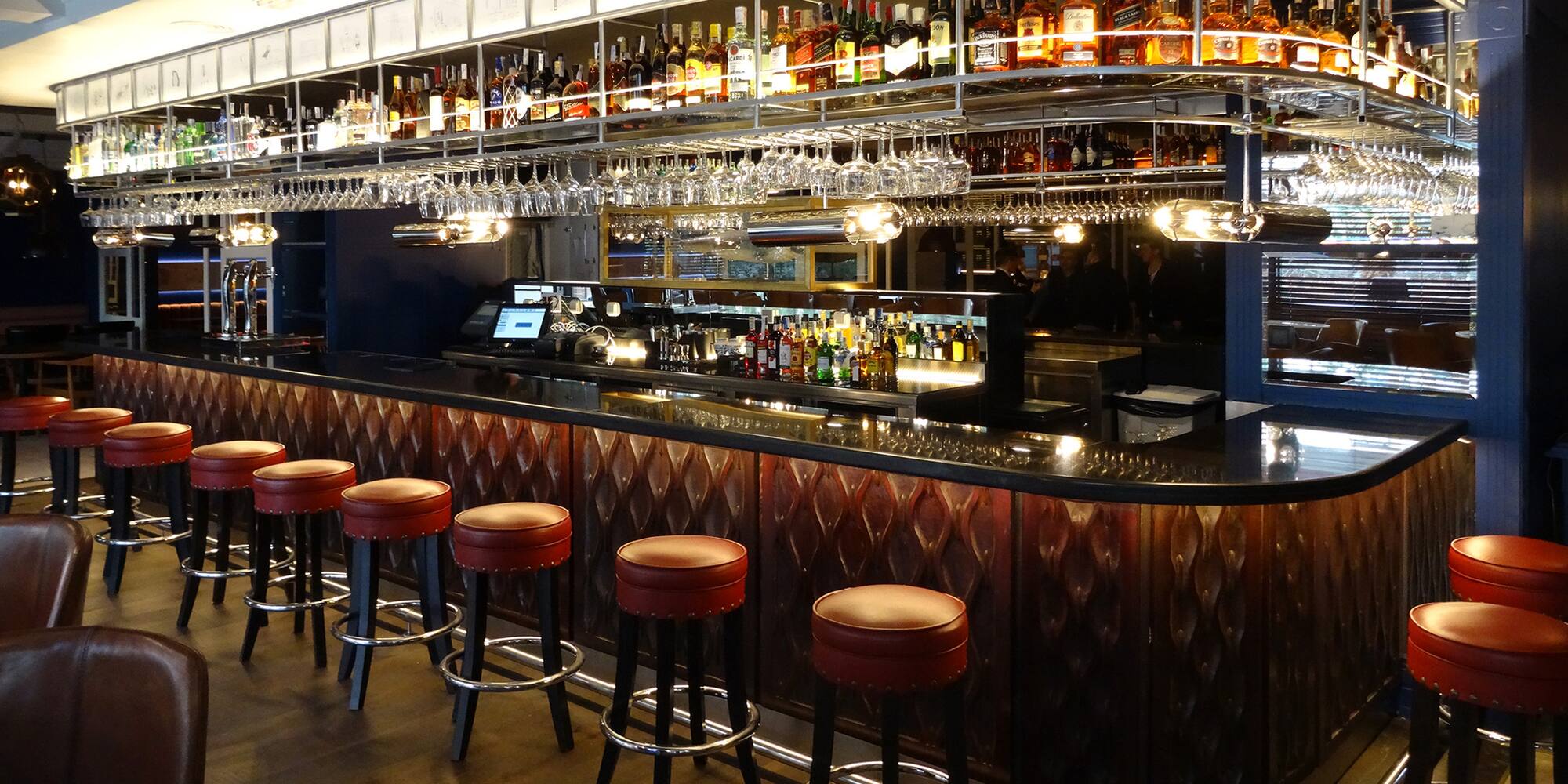 a bar with a row of stools and bottles