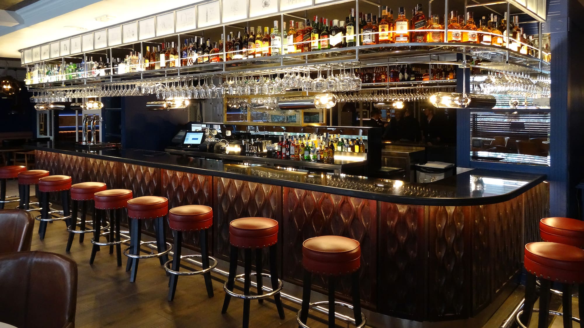 a bar with a row of stools and bottles