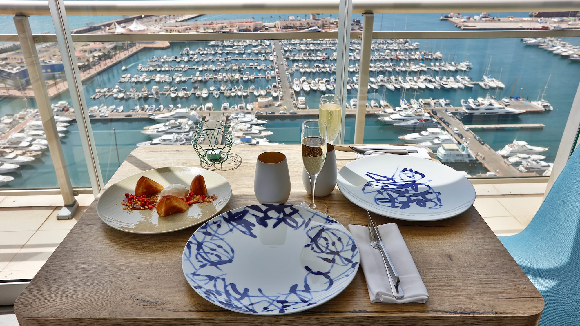 a table with plates and glasses on it and a view of a marina