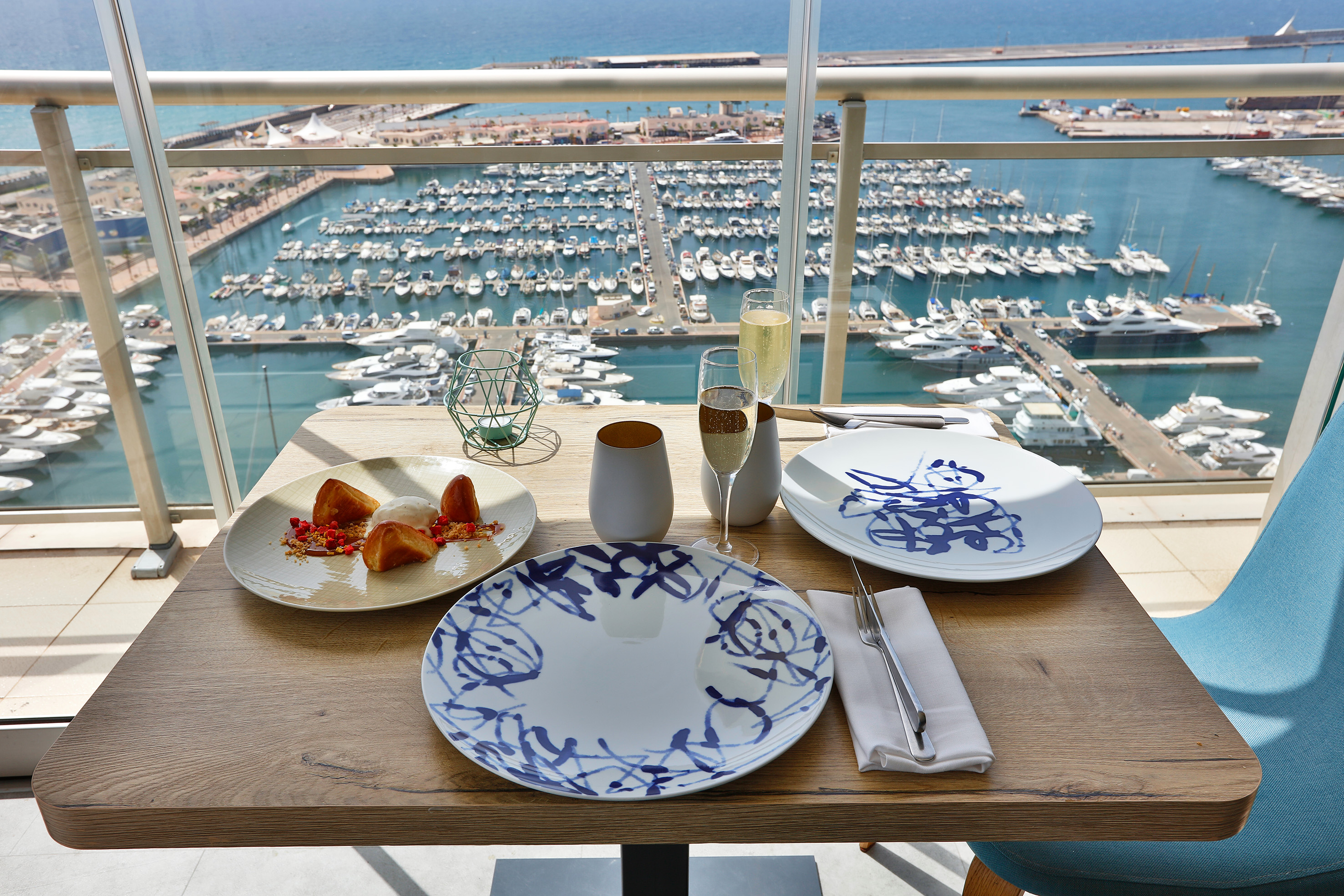 Balcony dining with dessert and champagne, overlooking a marina full of yachts.