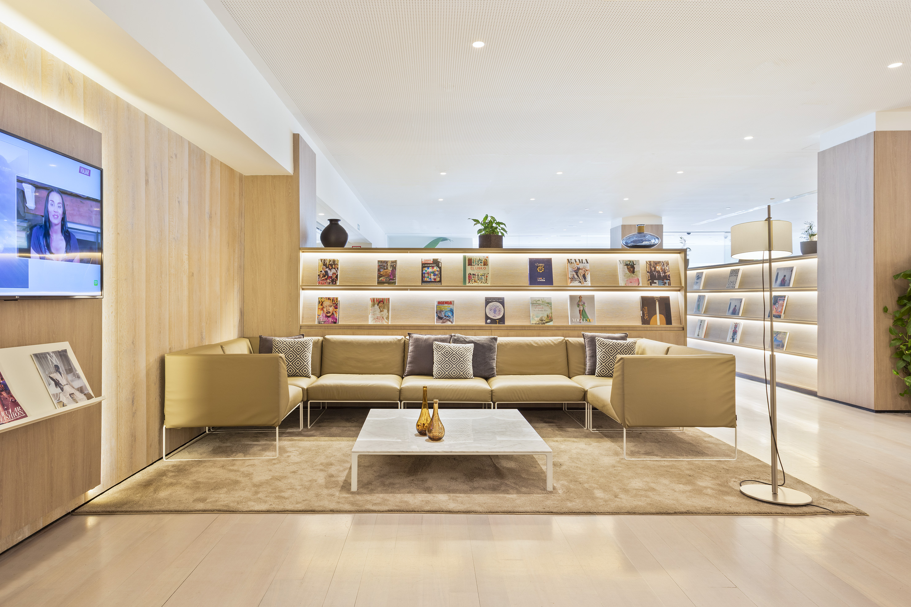 Modern hotel lounge with comfortable sofa, coffee table, and lit magazine wall.
