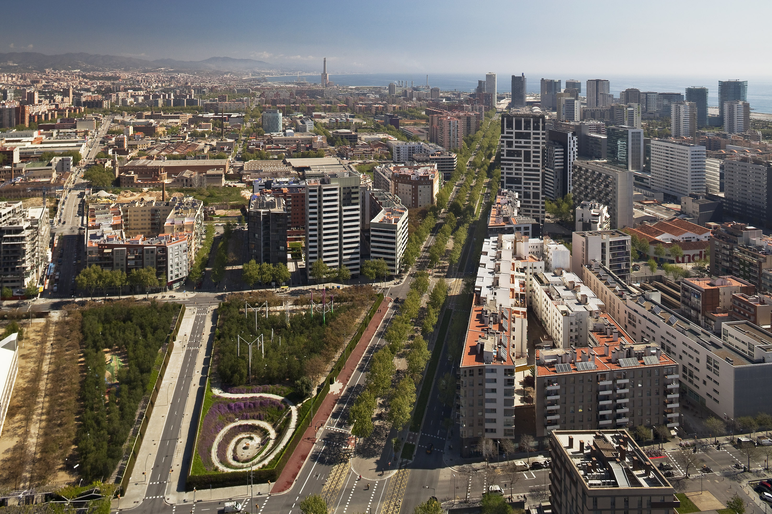 Aerial view of Barcelona city skyline, modern buildings, urban park, and sea.