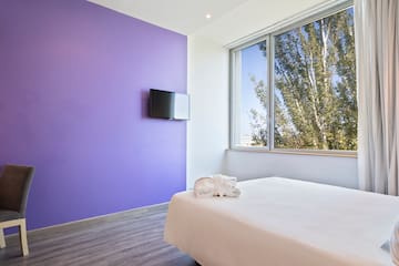 a bed in a room with purple walls and a television