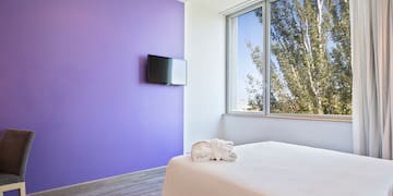 a bed in a room with purple walls and a television
