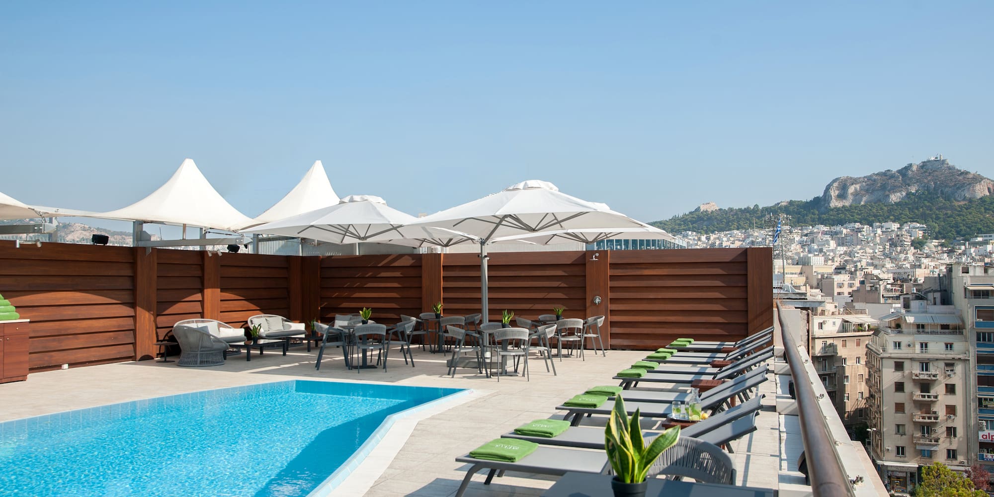 a pool with chairs and tables on a rooftop