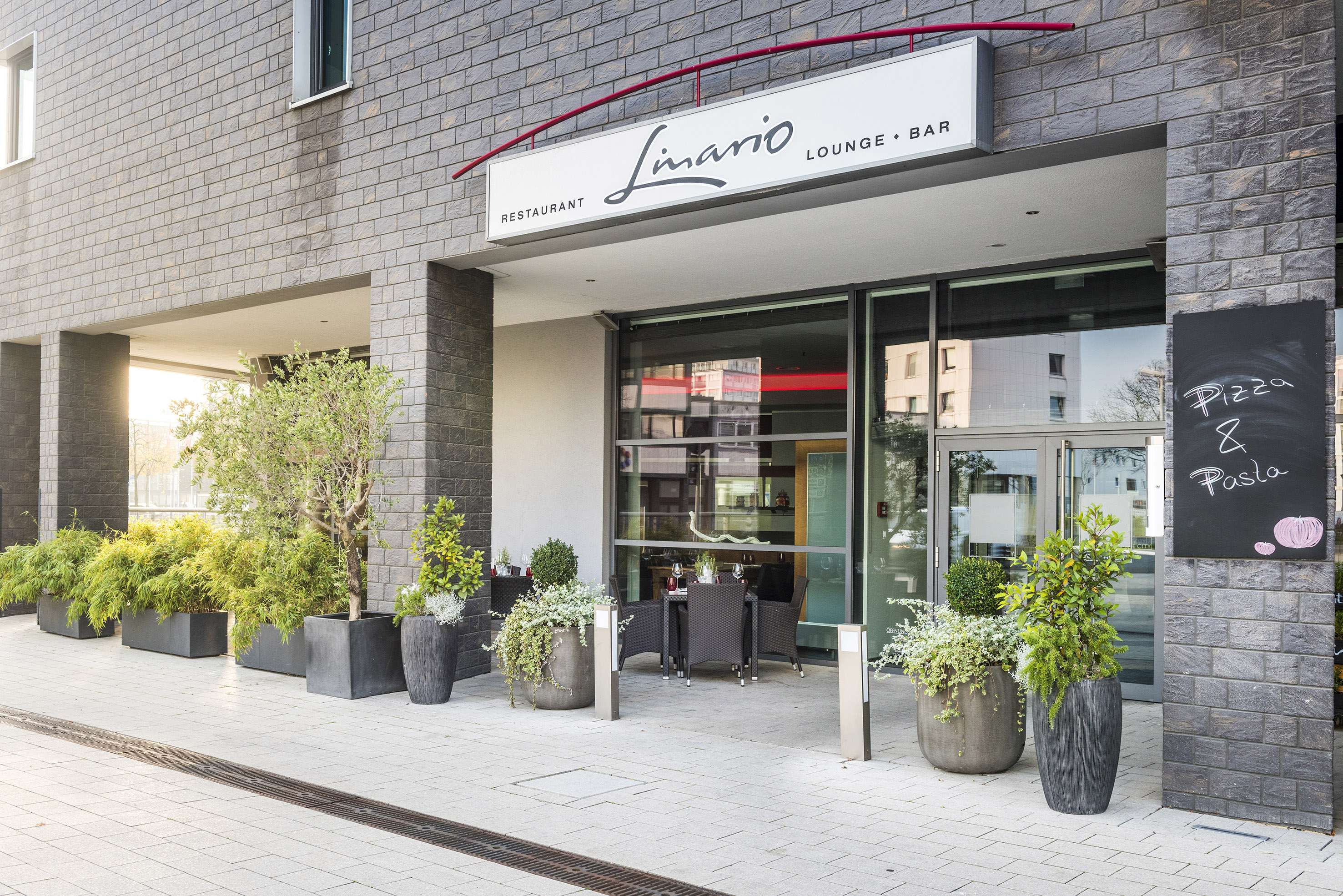 Limanio Restaurant exterior with outdoor patio dining and green plants.