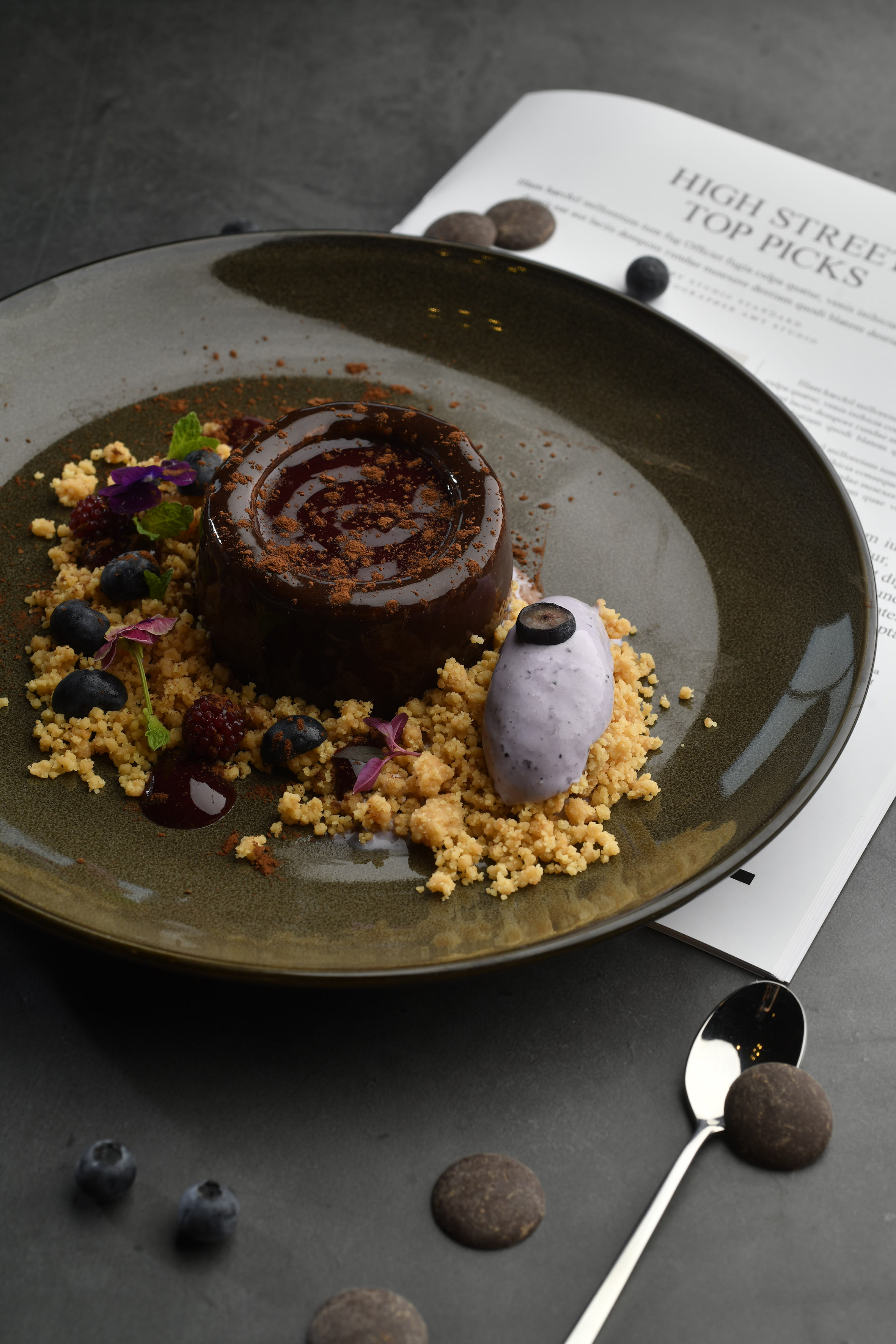 Dark chocolate pudding with blueberry ice cream, berry crumble, and edible flowers.