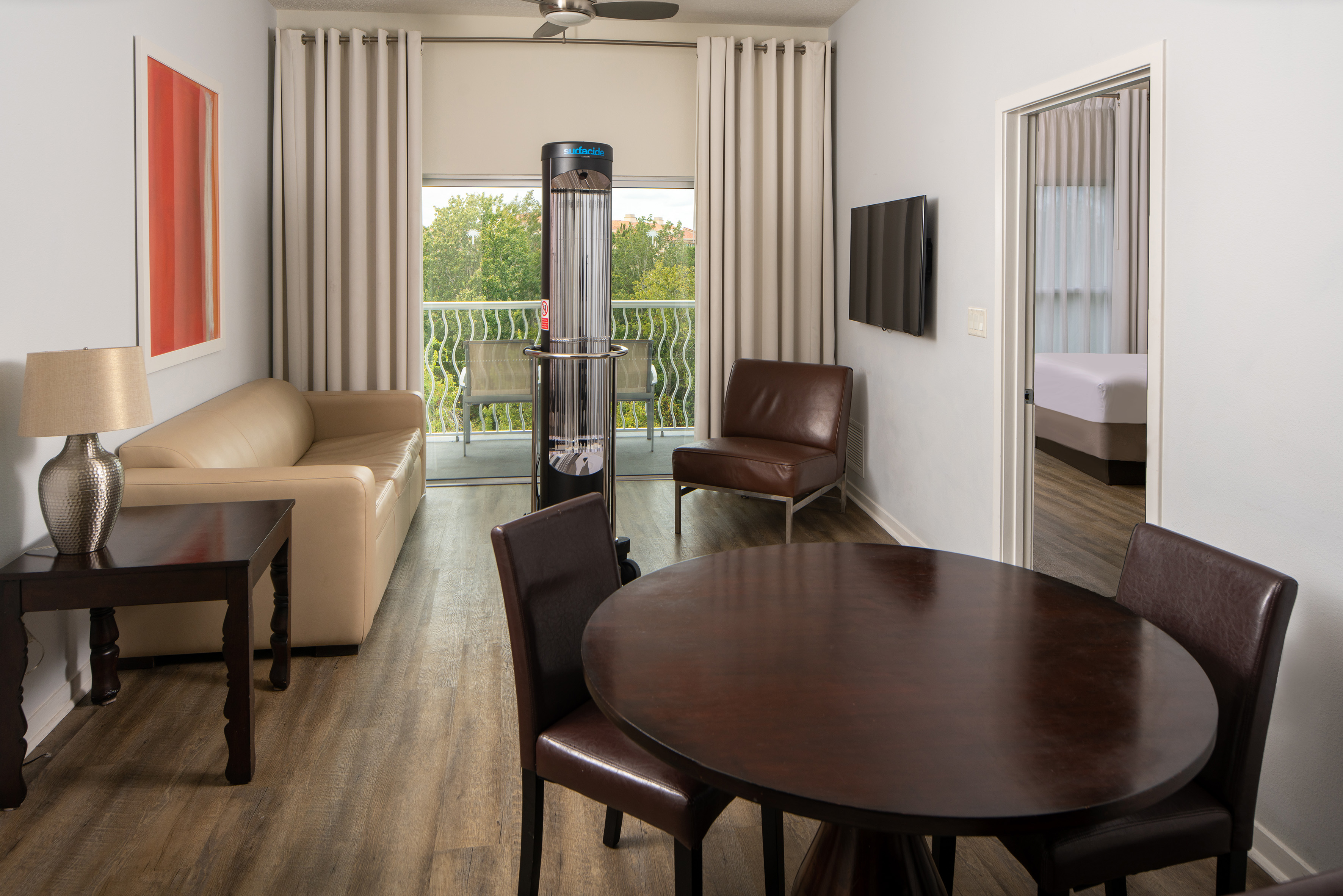 Hotel suite living/dining, sofa, balcony, Surfacide UV robot.