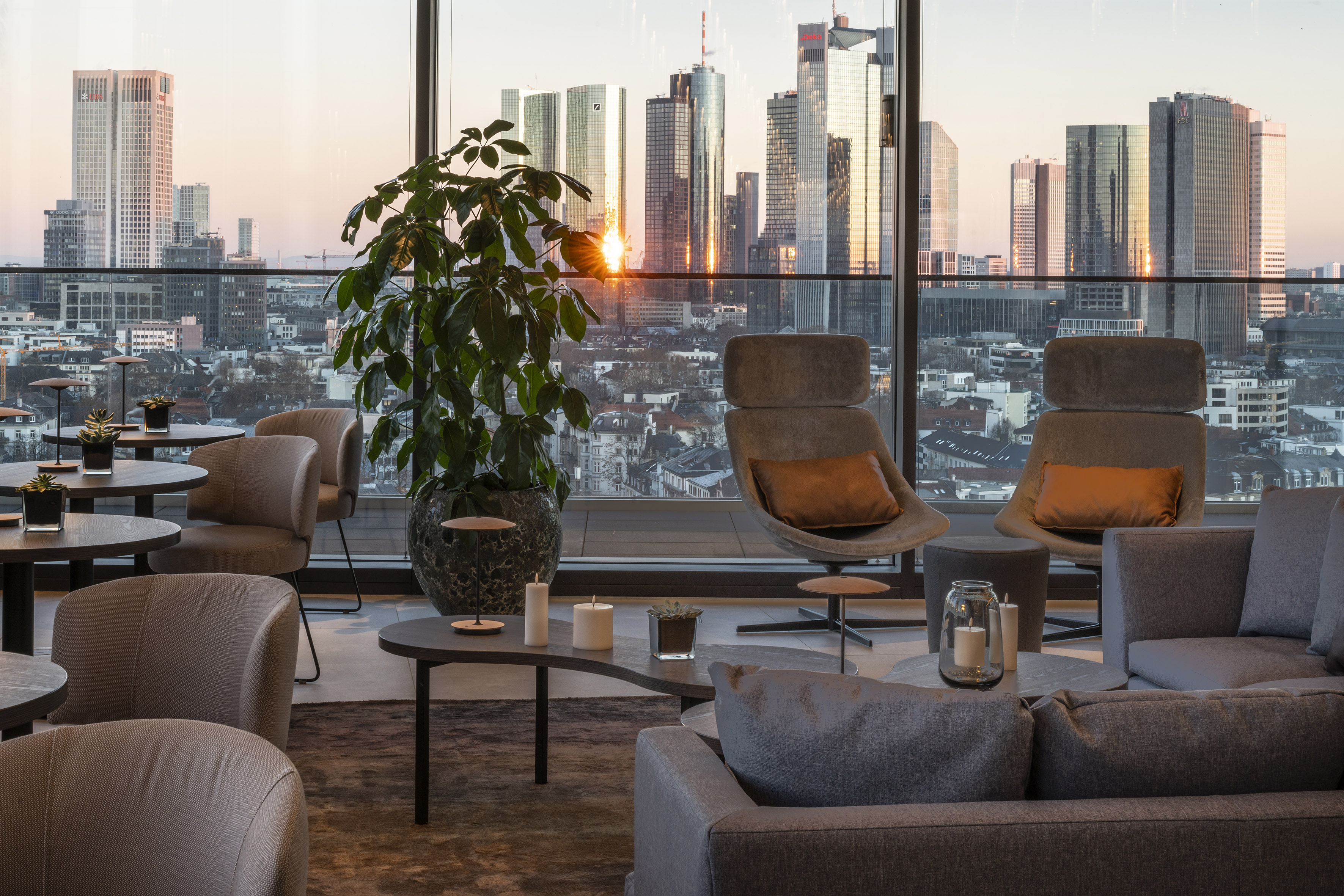 Luxury lounge interior with panoramic city skyline at sunset.