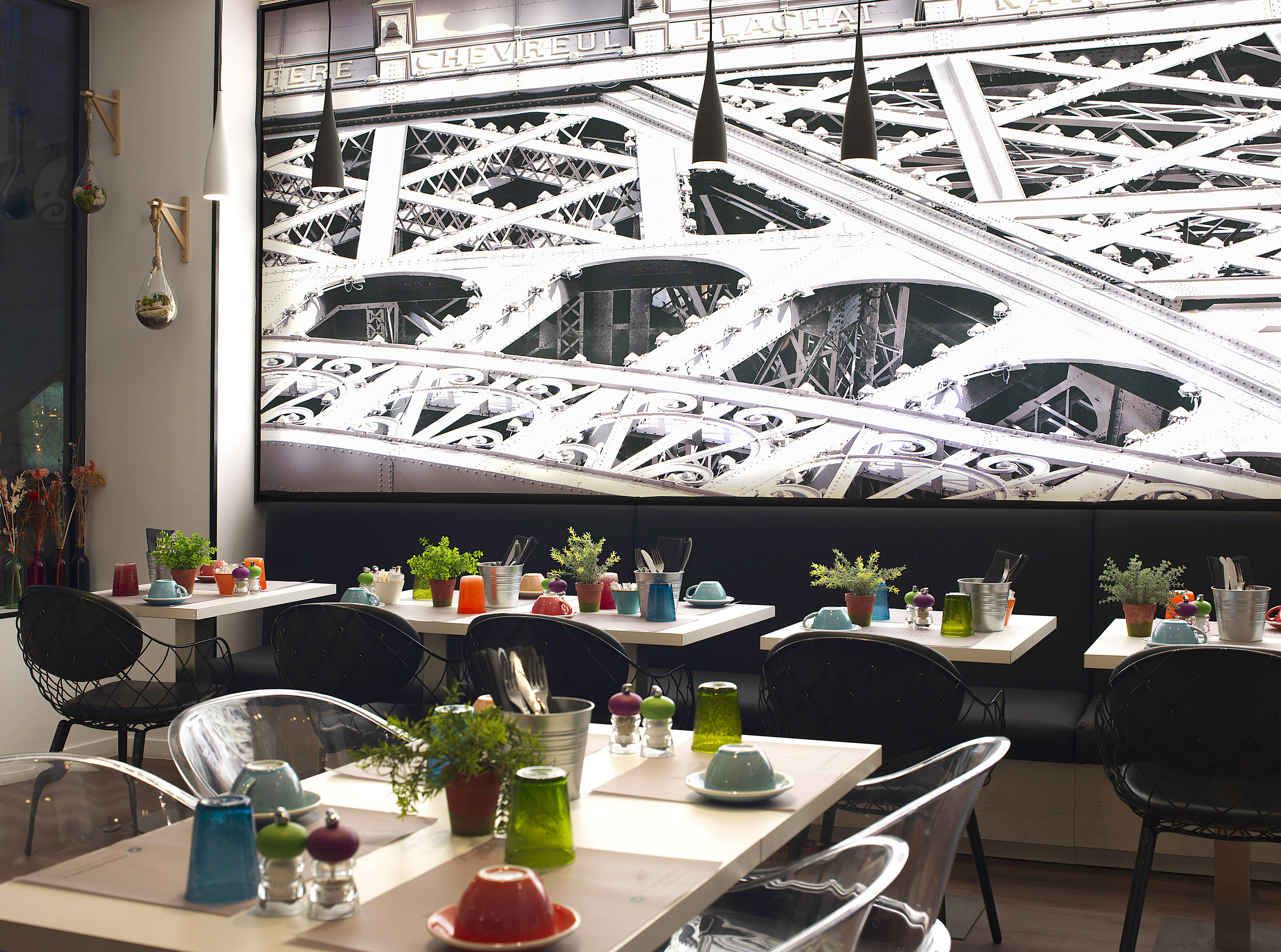 Modern cafe dining area with Eiffel Tower mural and colorful table settings.