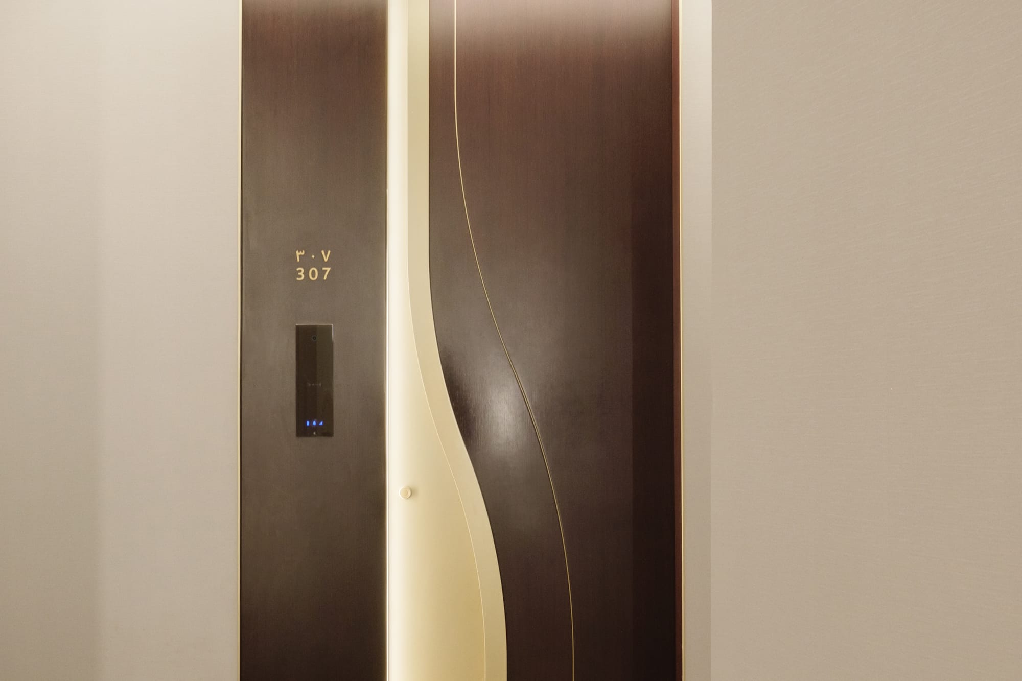 Modern dark door 307 with curved illuminated panel in a hotel hallway.