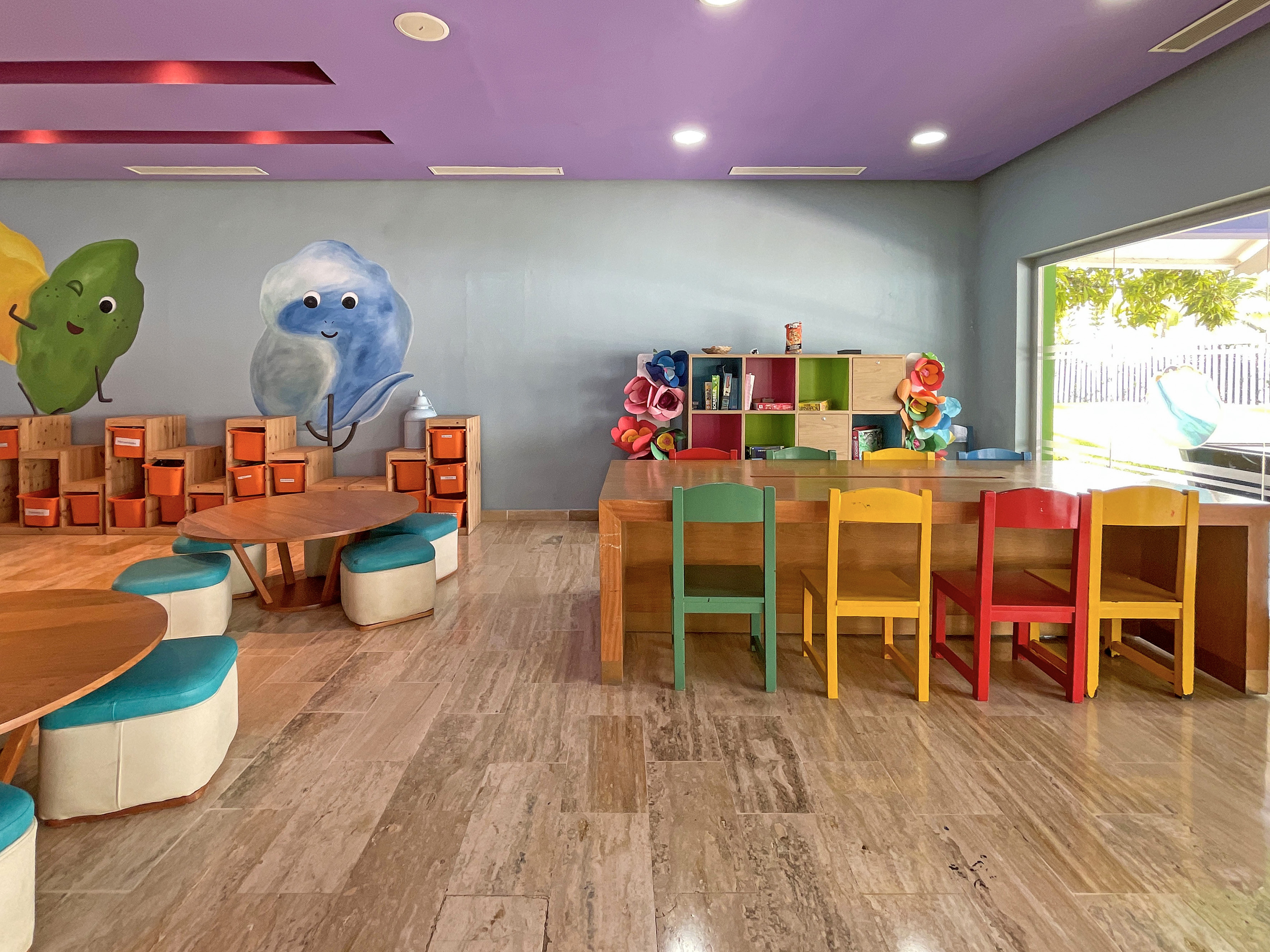 Colorful kids' playroom with cartoon wall art and child-sized furniture.