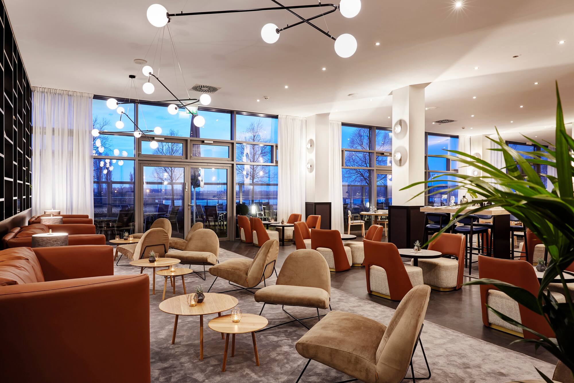 Modern hotel lounge with varied seating, modern lighting, and water view.