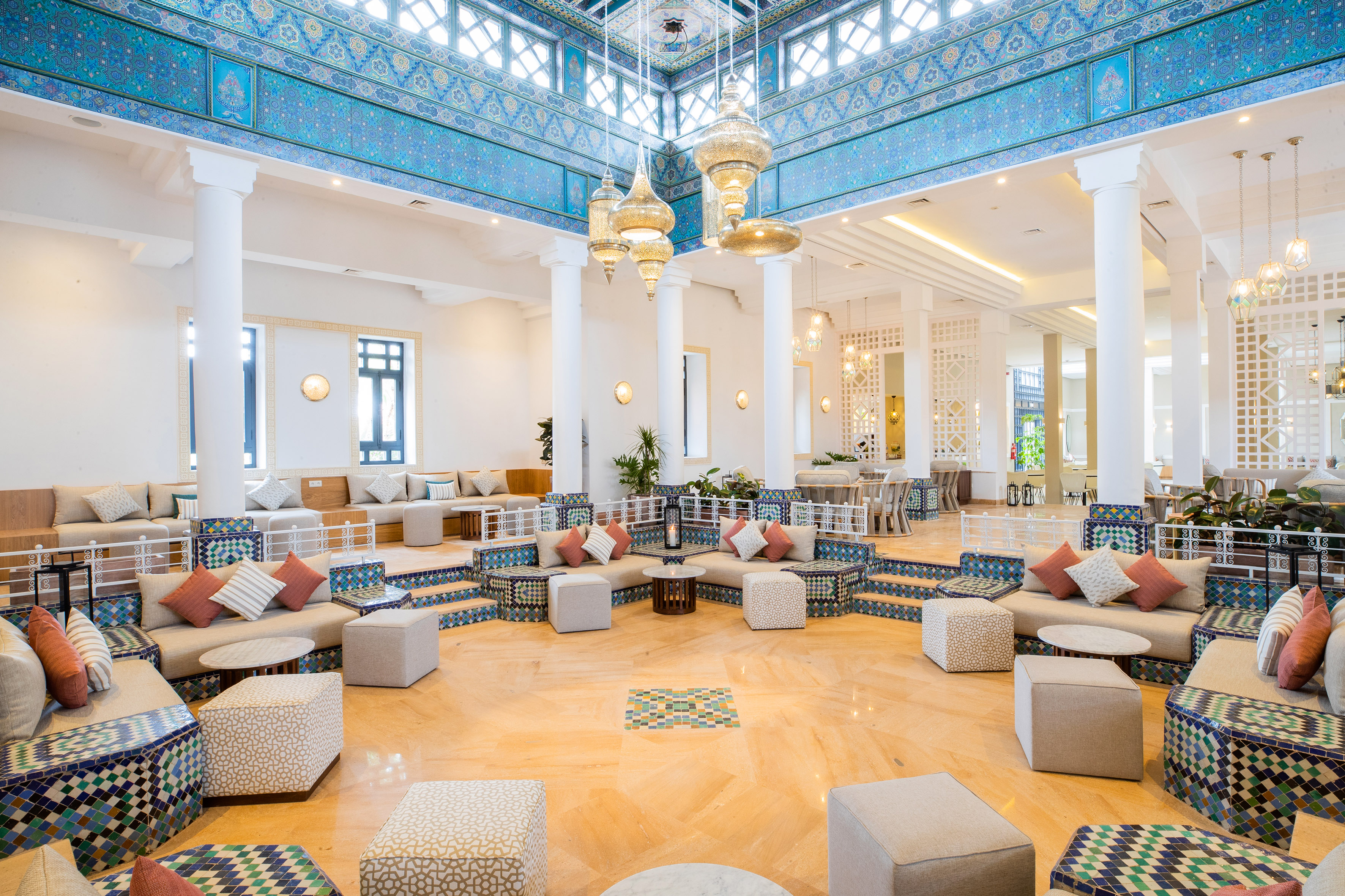 Moroccan resort lounge with blue mosaic tiles, ornate chandeliers, and plush seating.