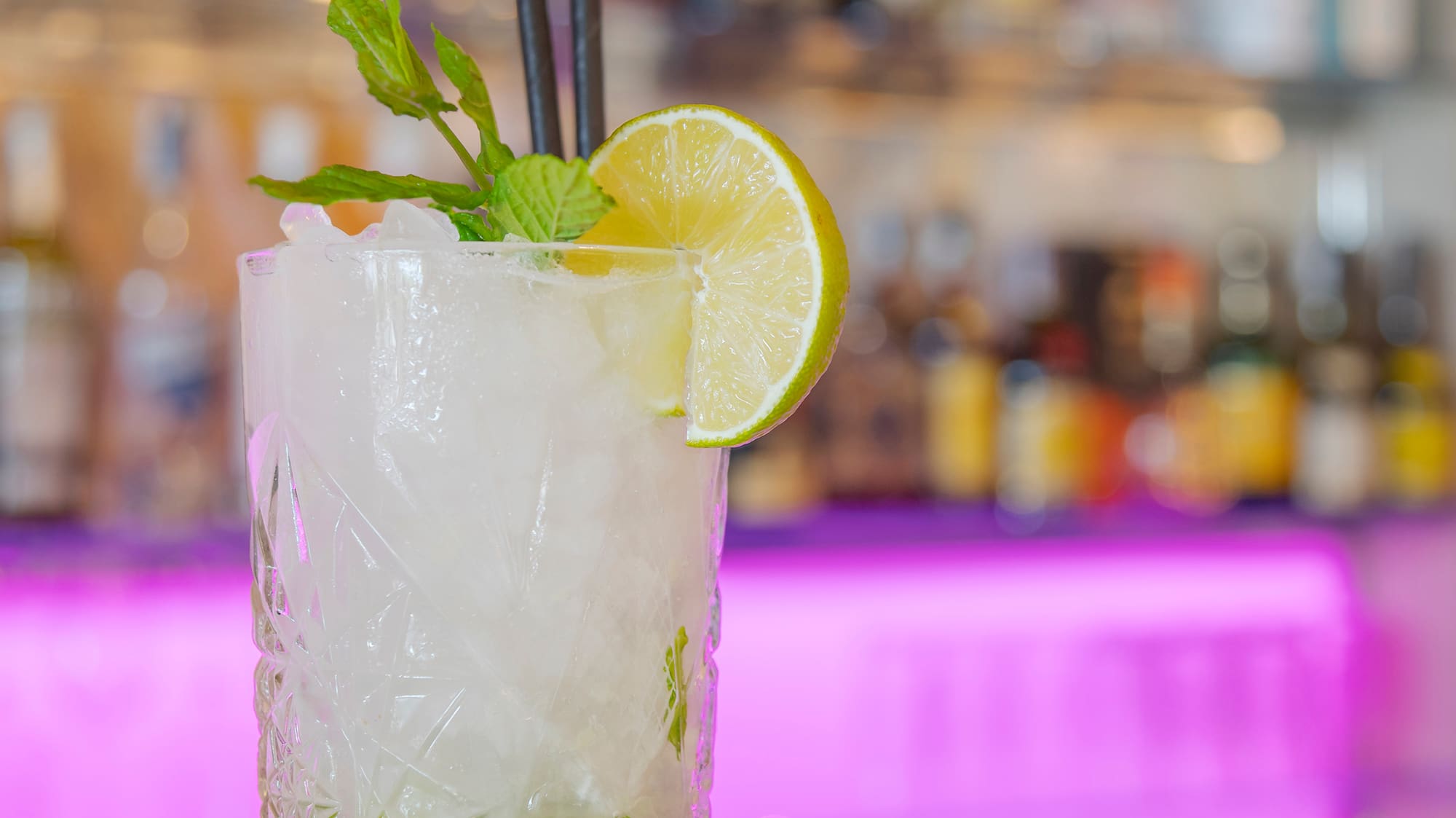 a glass with a drink and a slice of lime and mint