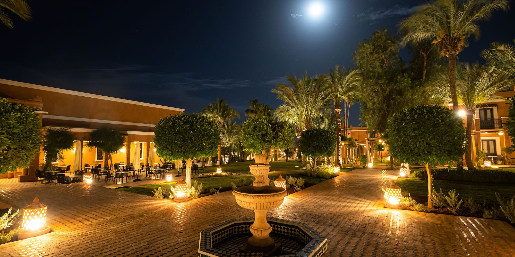 a fountain with trees and lights in front of a building