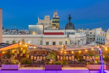 a rooftop patio with chairs and trees in the foreground