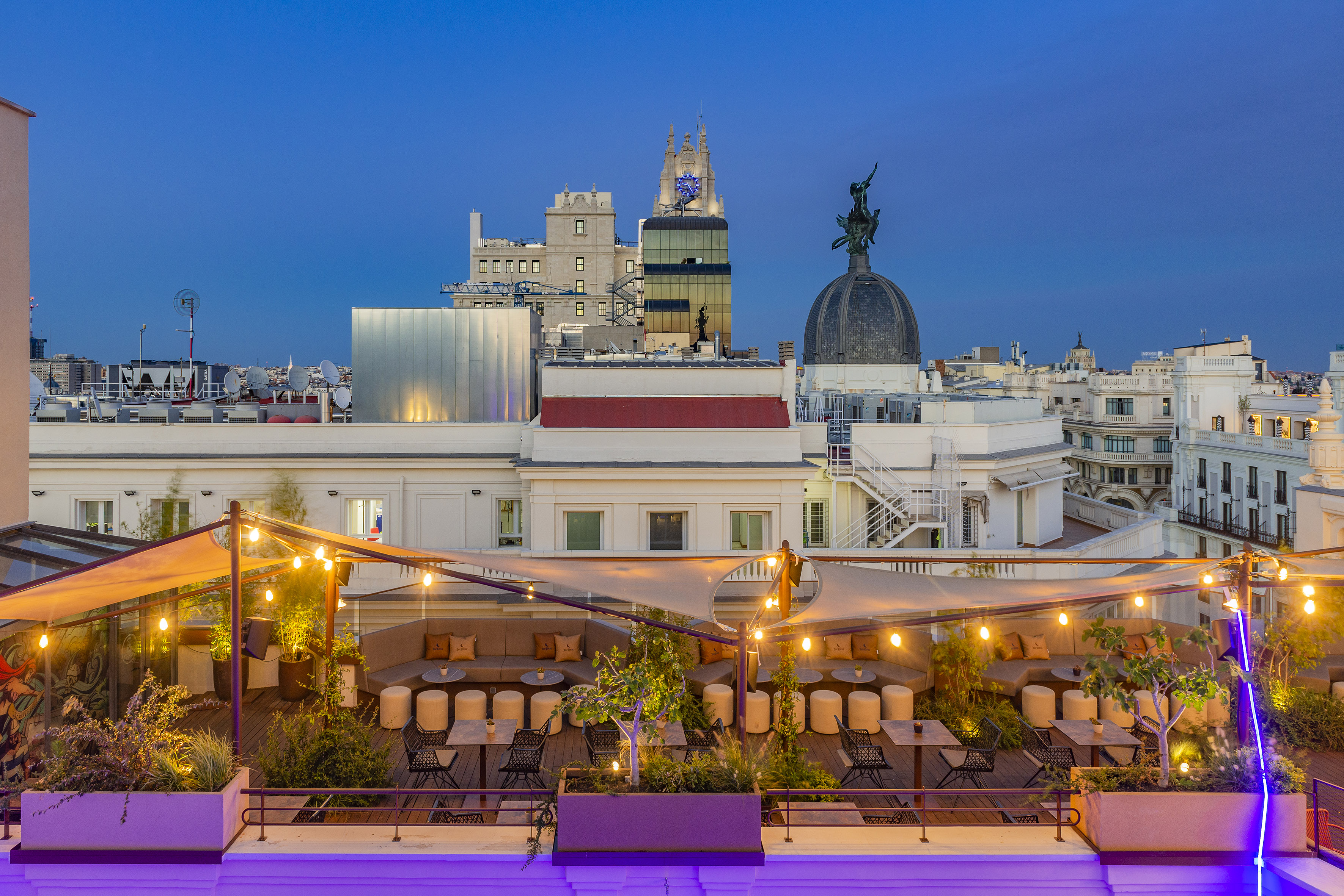 A rooftop terrace featuring chairs and trees in the foreground.
