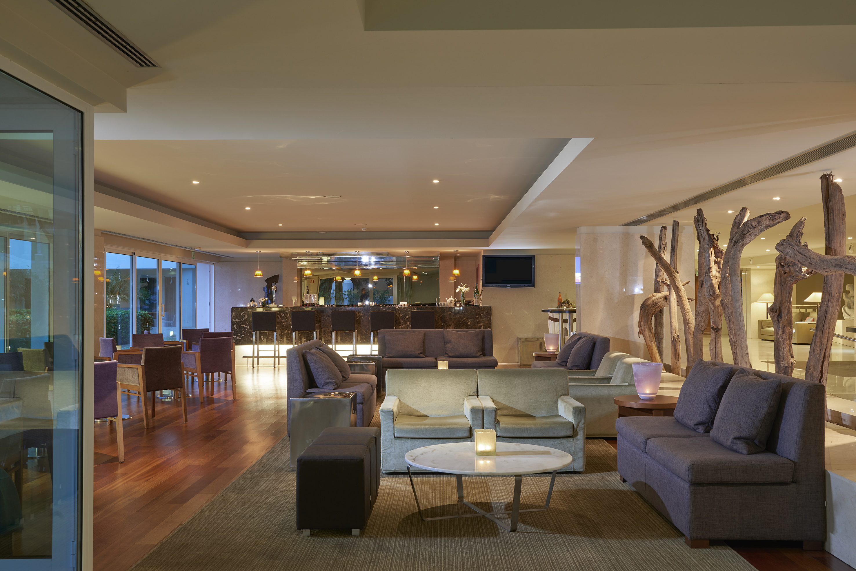 Contemporary hotel lounge featuring a bar, plush seating, and large windows.