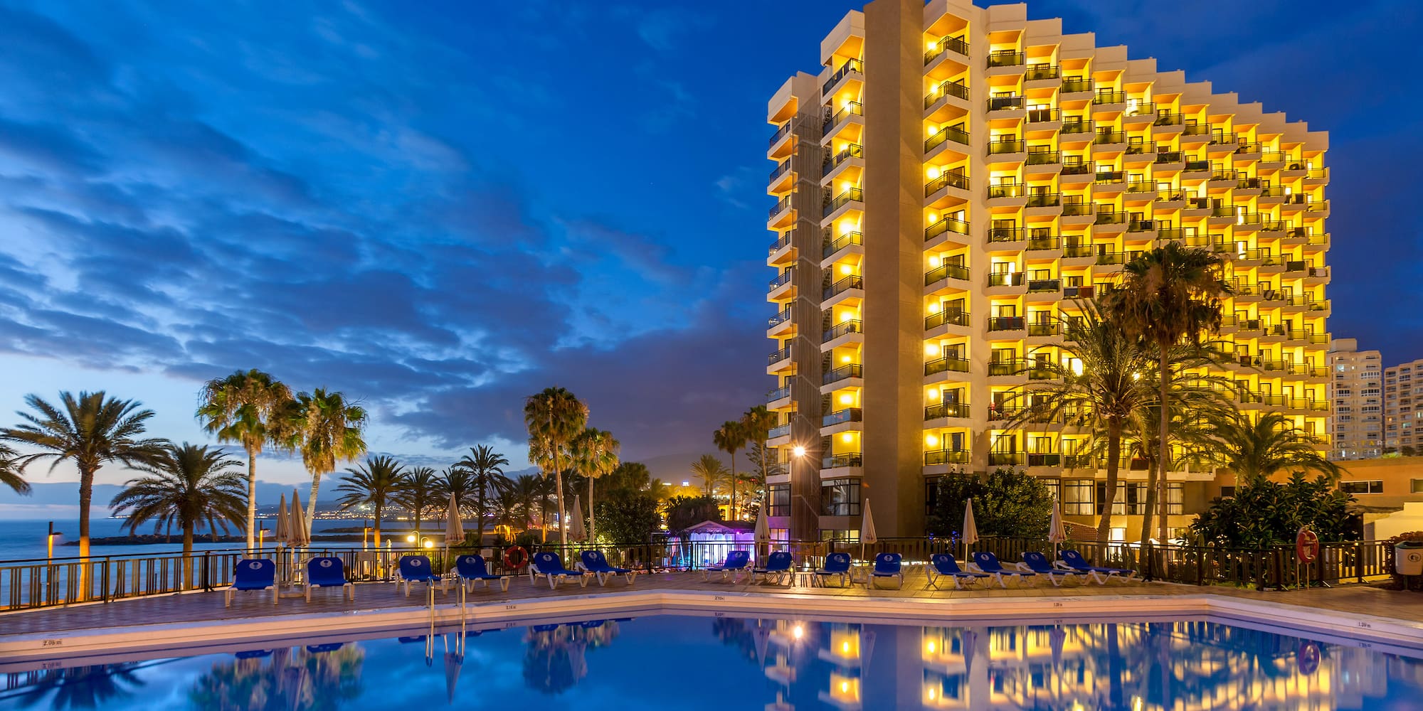a building with lights on the outside of a pool
