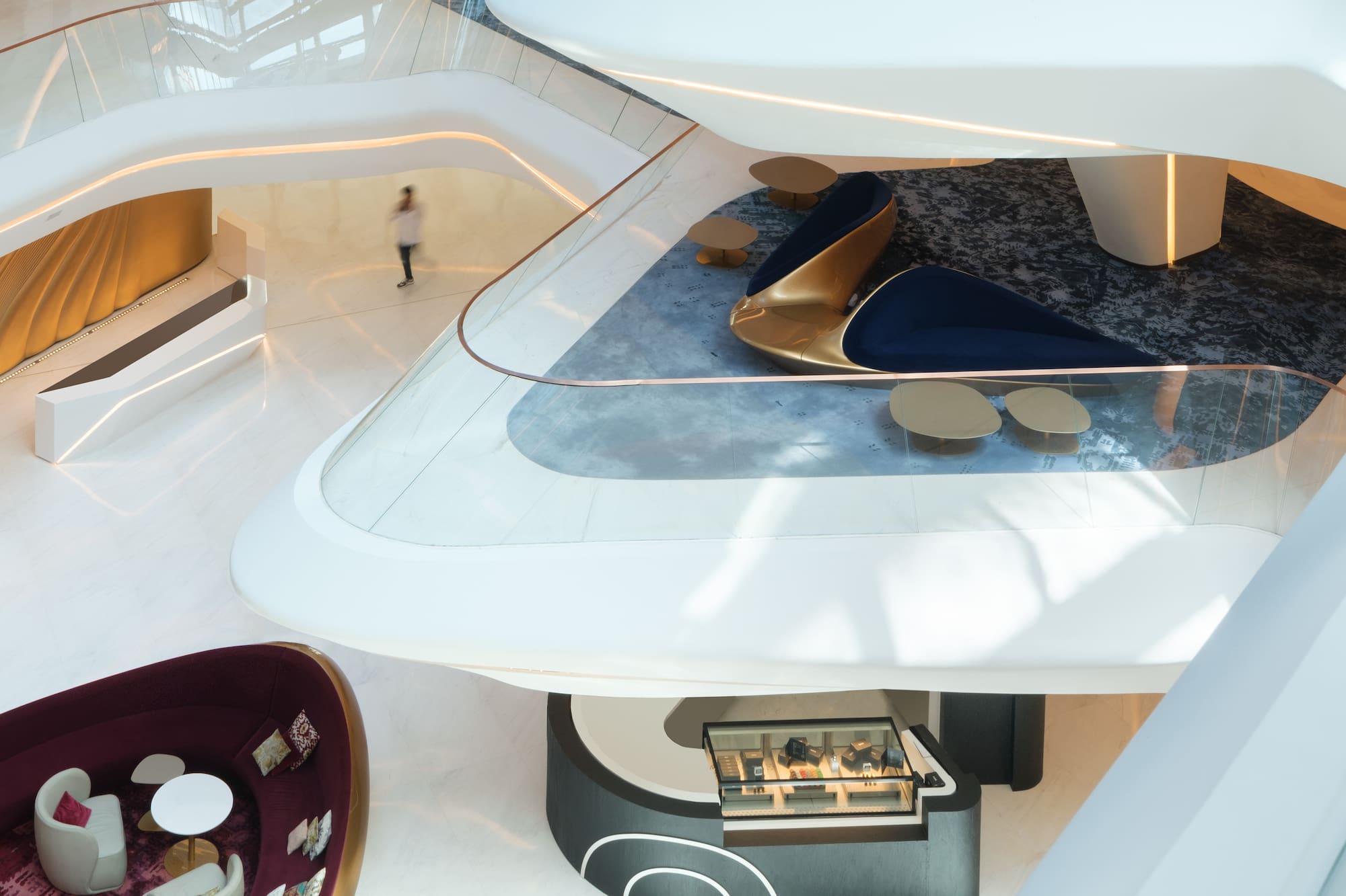 Modern multi-level luxury lobby with curved walls, plush seating, and retail.