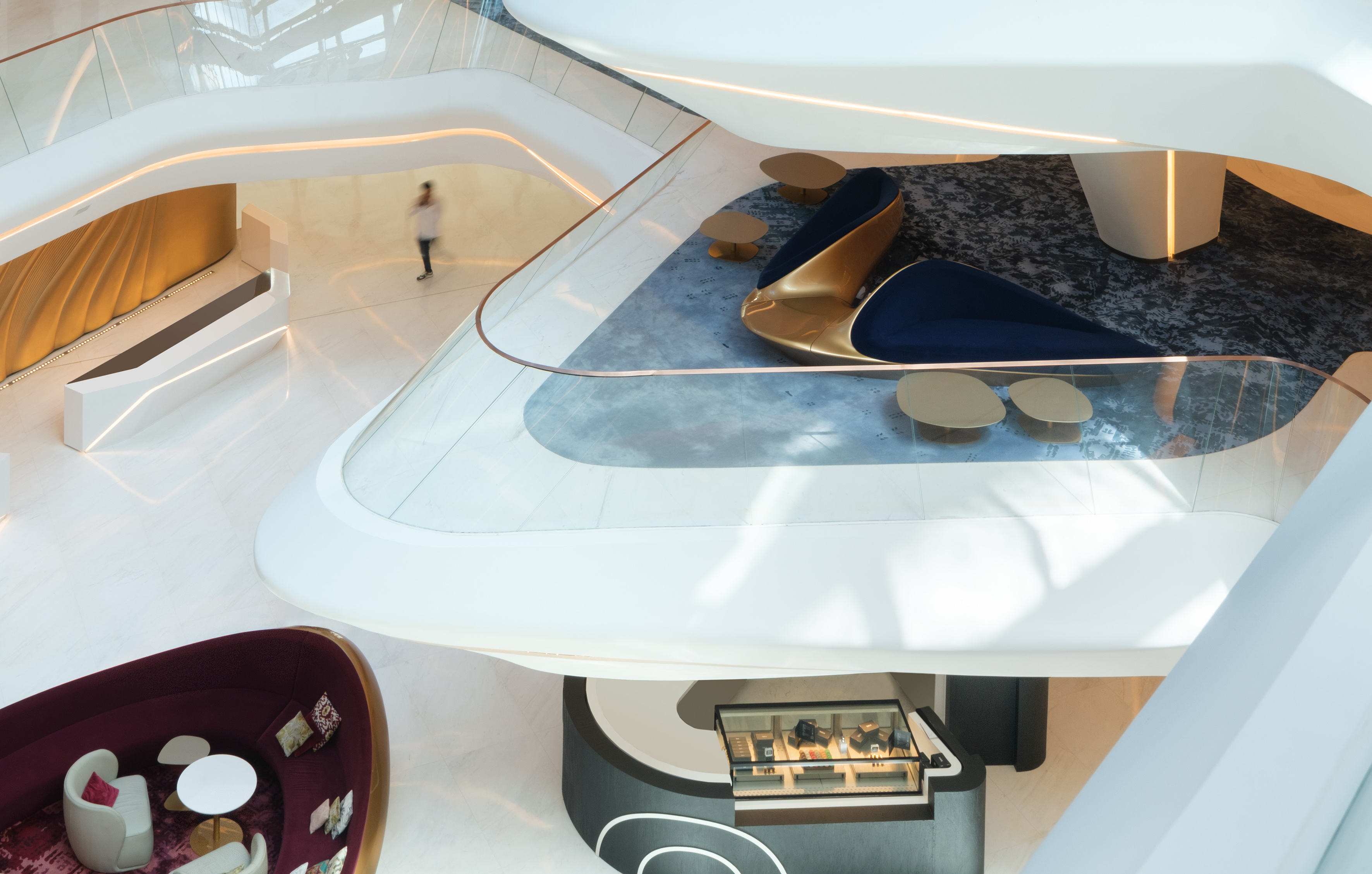 Modern multi-level luxury lobby with curved walls, plush seating, and retail.