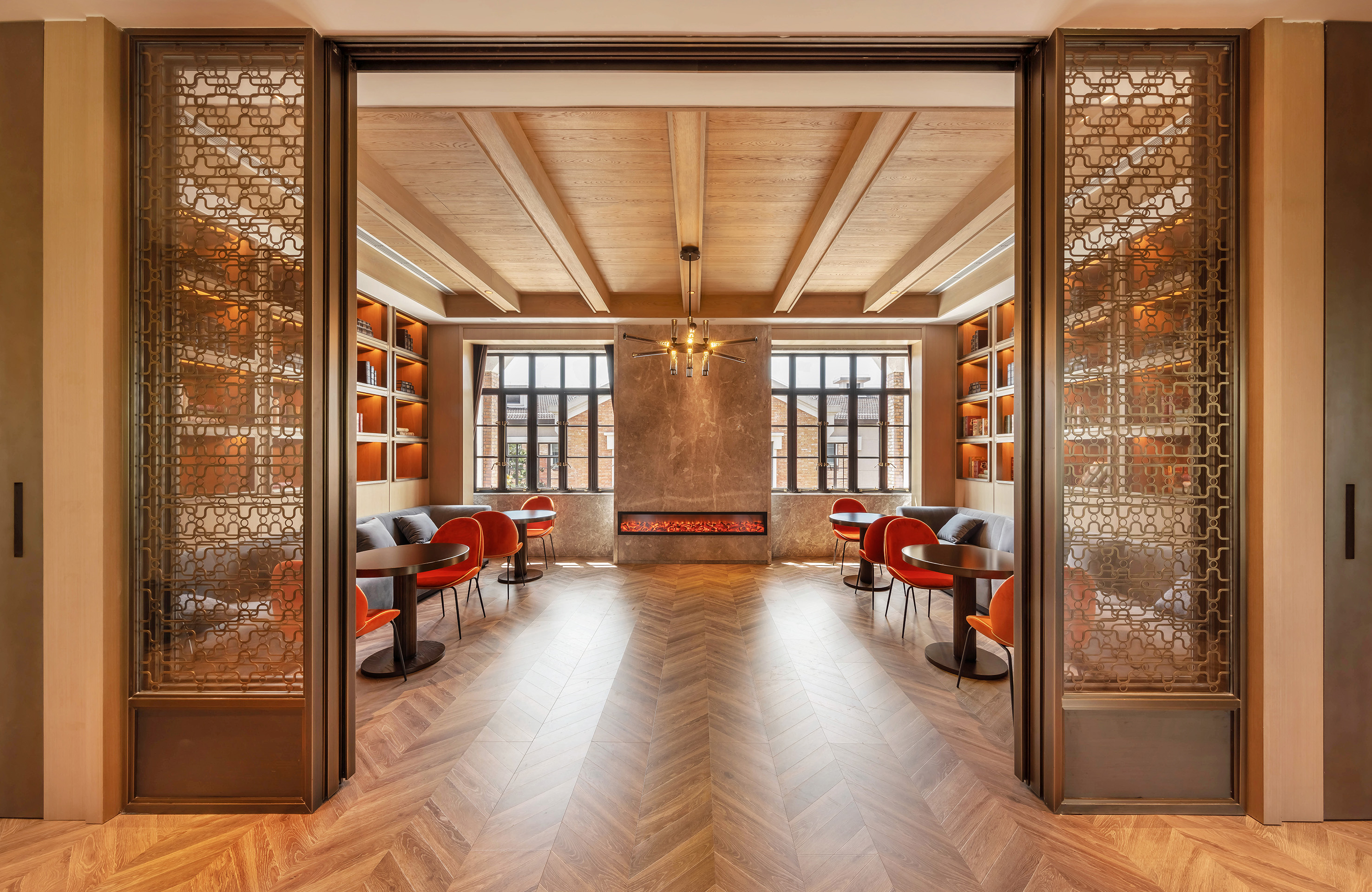 Luxury lounge with herringbone floor, modern fireplace, and orange chairs.