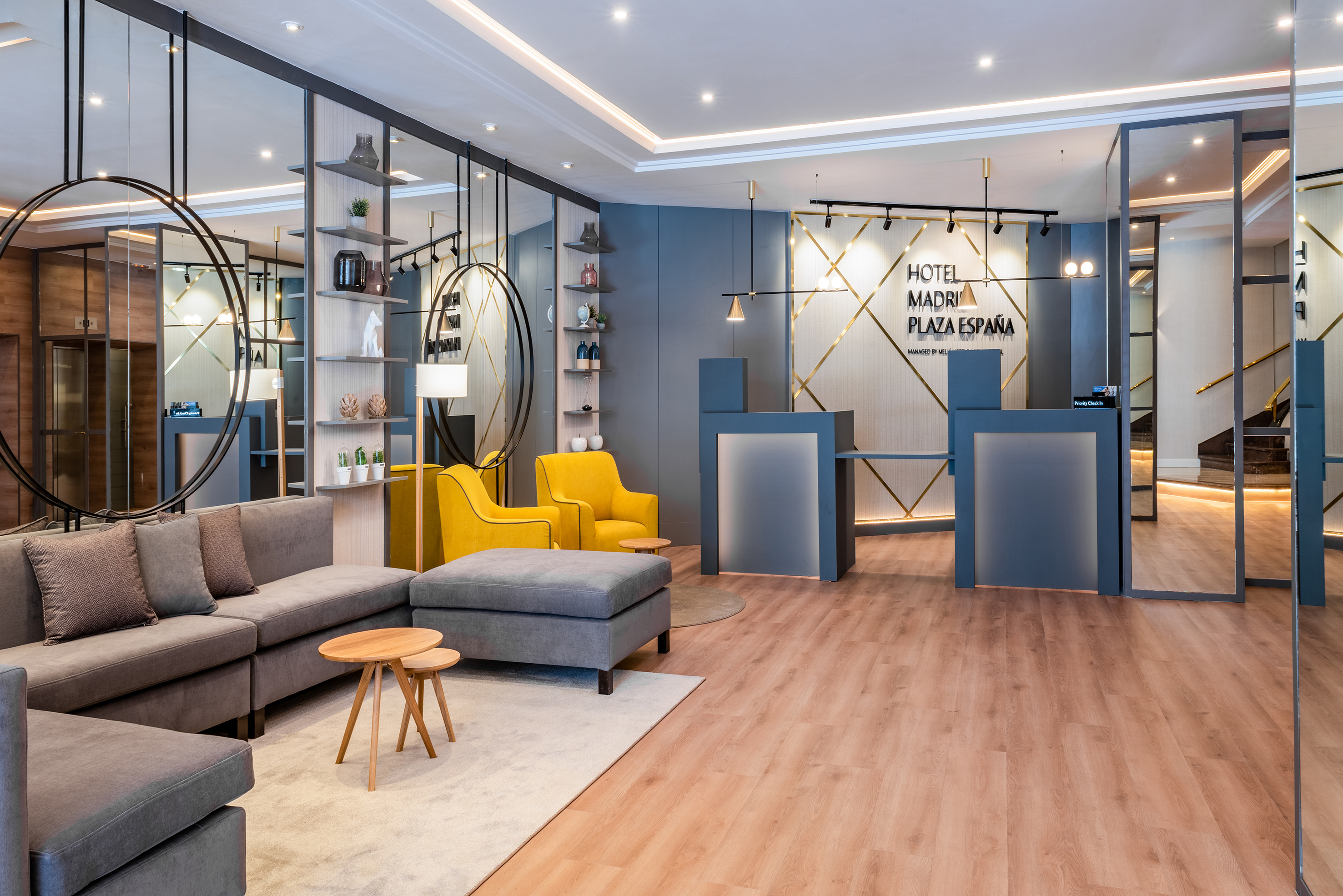 Madrid Plaza España hotel lobby: modern reception, grey sofa, yellow armchairs.
