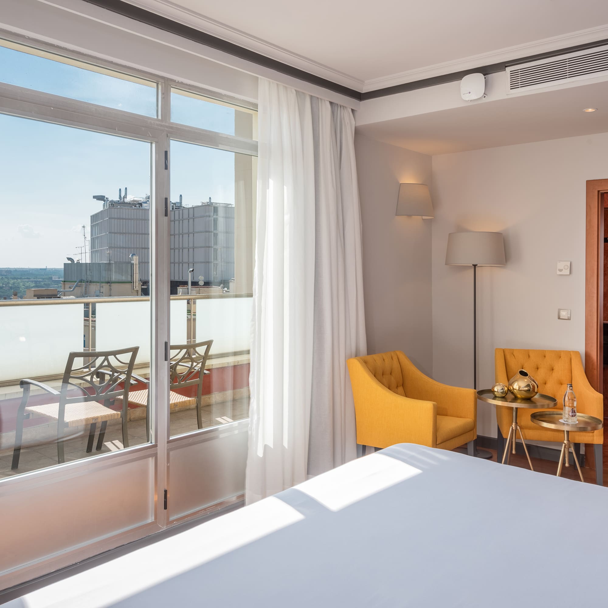 a room with a bed and chairs and a balcony