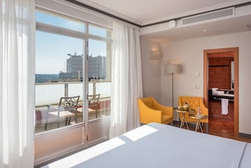 a room with a bed and chairs and a balcony