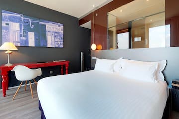 a bed with white sheets and a desk in a room