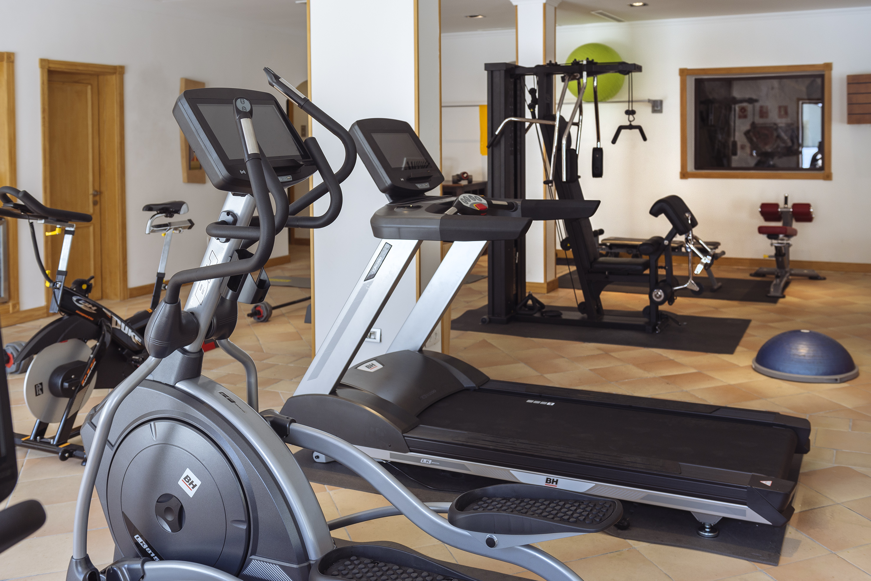 Gym with treadmill, elliptical, stationary bike, and weight training equipment.