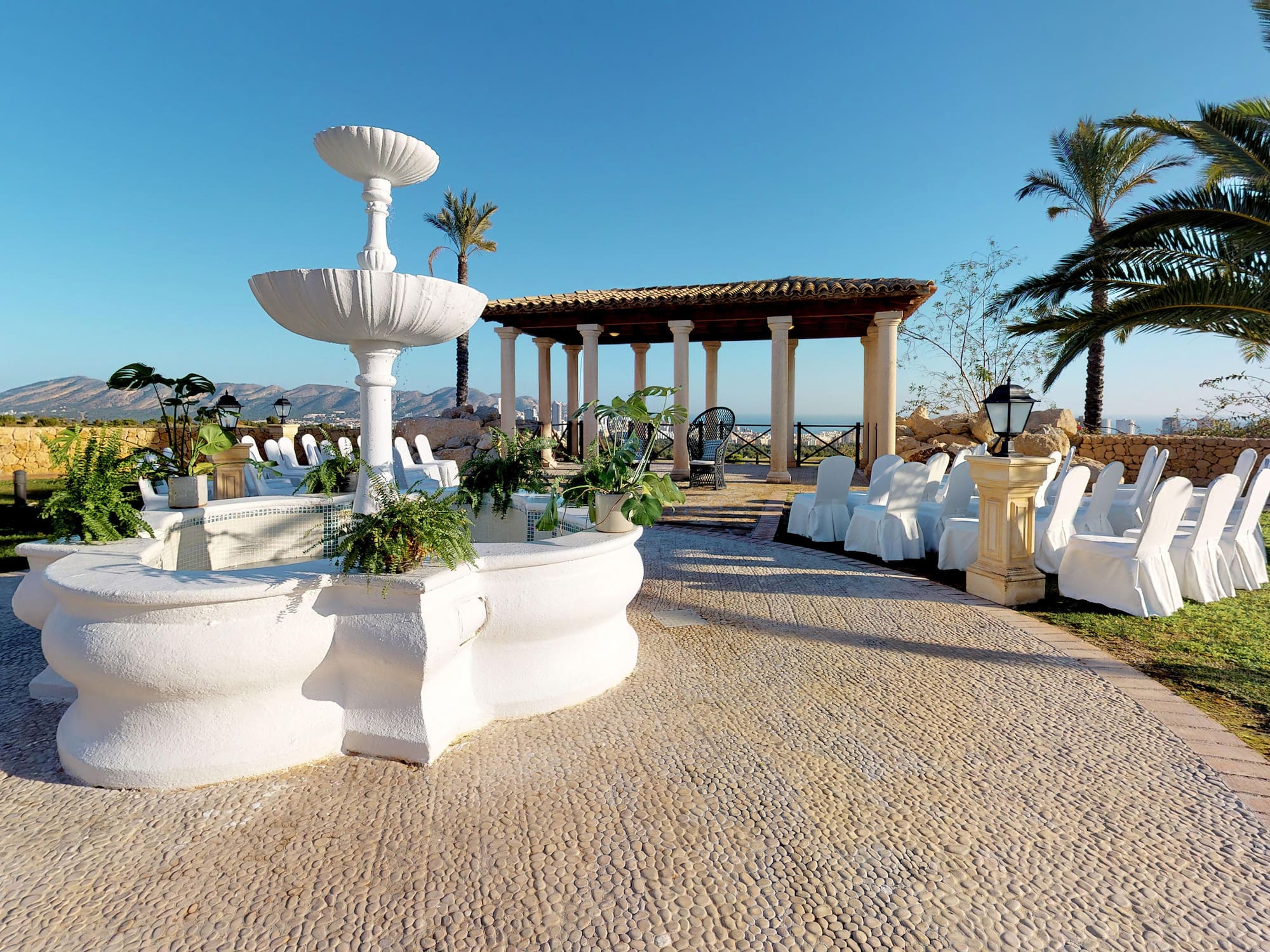 a white fountain with chairs and a gazebo