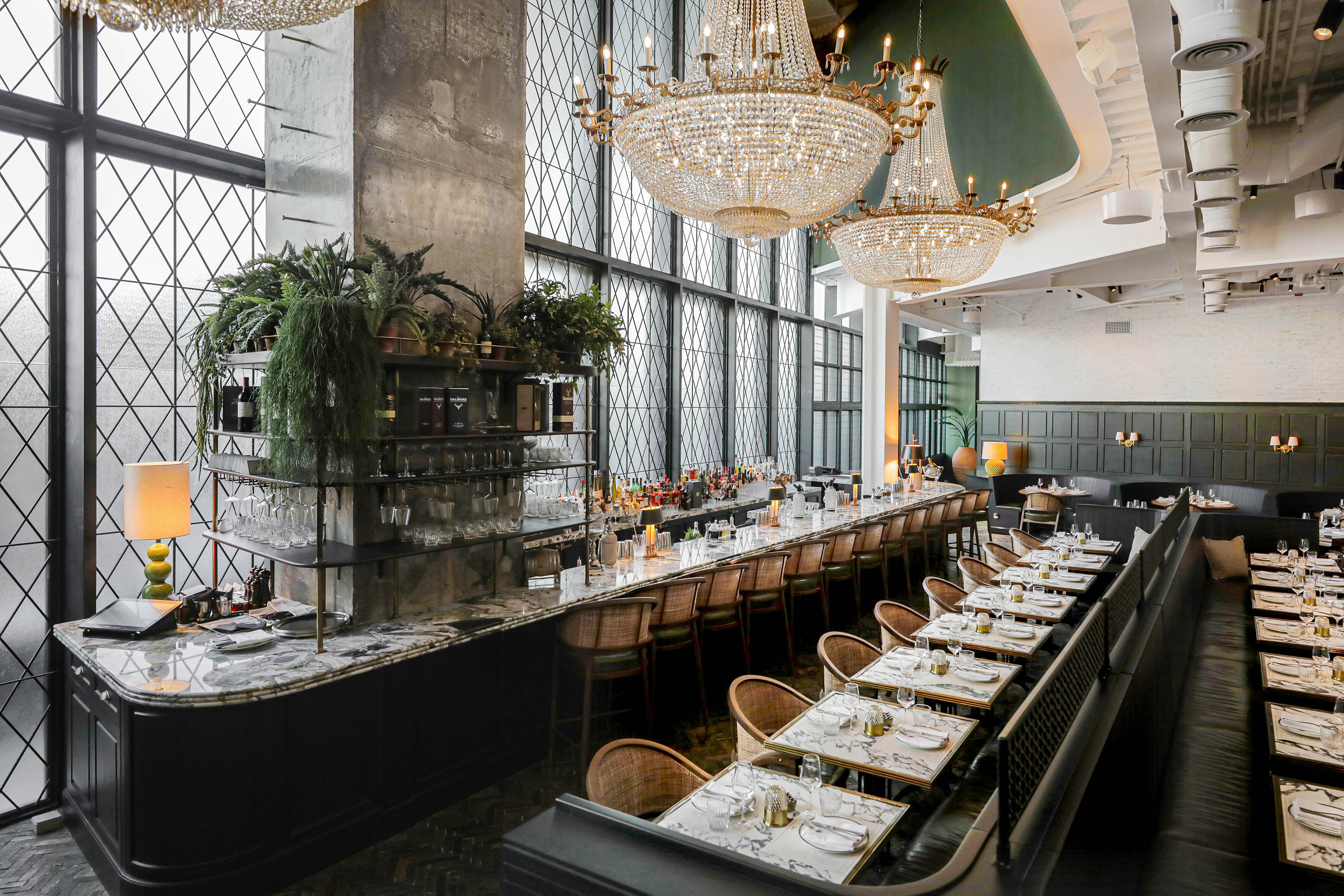 Luxury restaurant with marble bar, crystal chandeliers, and set dining tables.