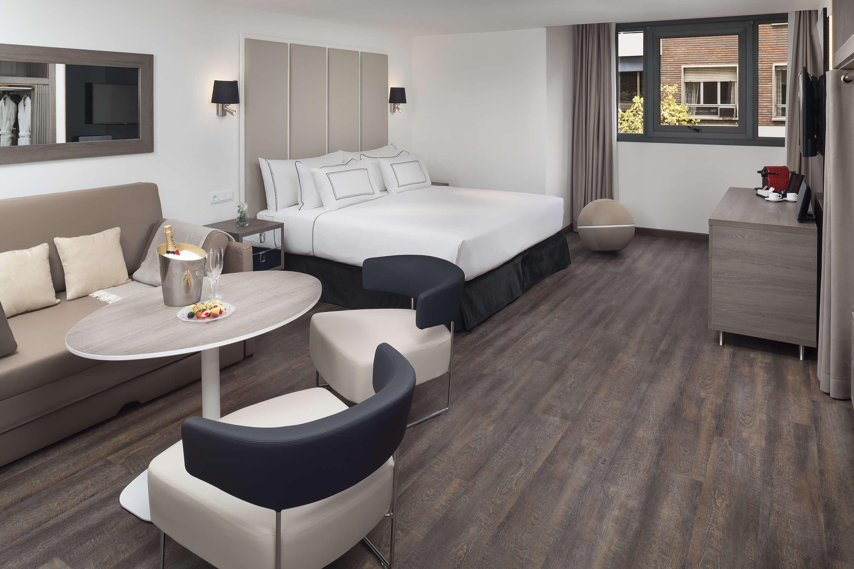Spacious hotel room with king bed, sofa, dining area, and coffee maker.
